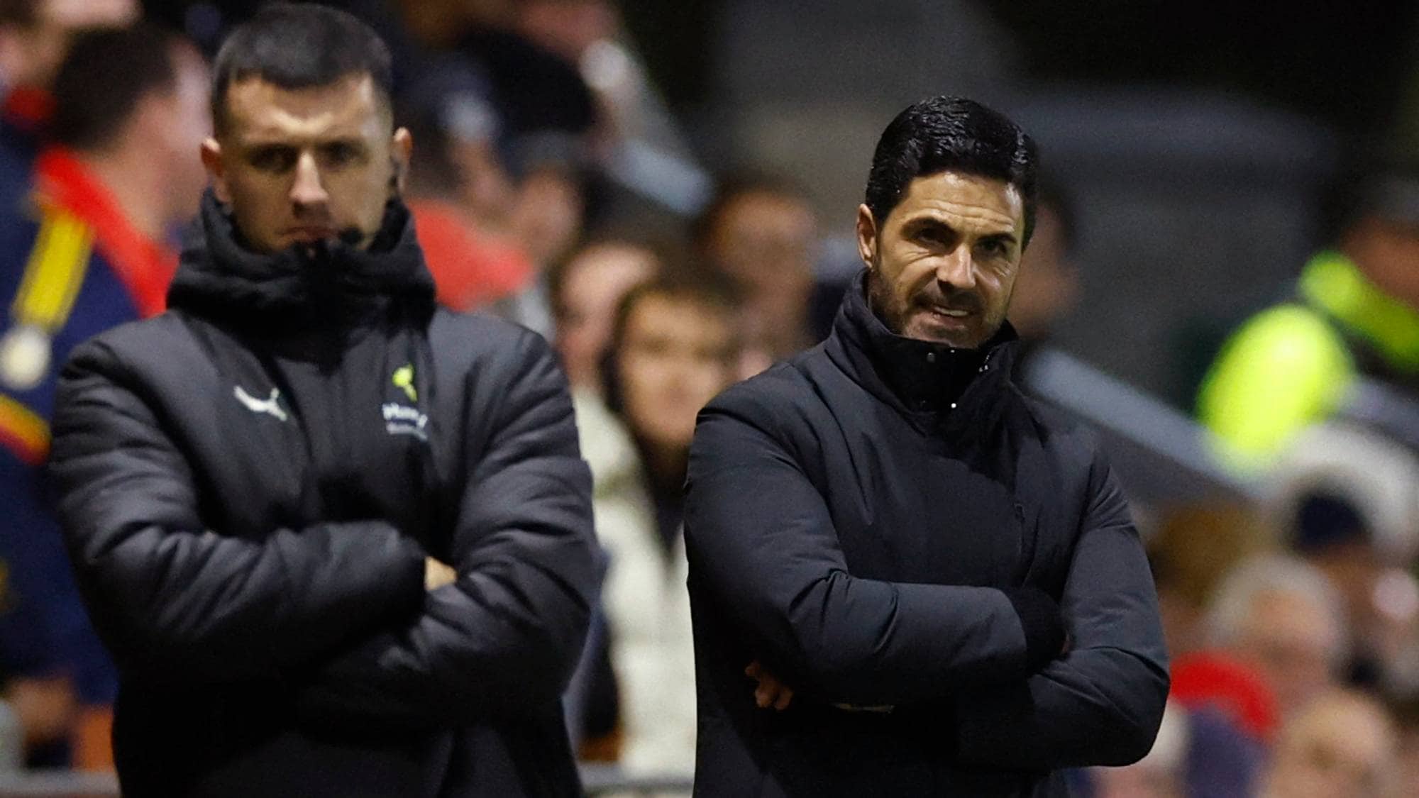 Mikel Arteta og en medarbeider står med armene i kors på sidelinjen under en fotballkamp. (Bildebeskrivelsen er laget av en KI-tjeneste)