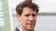 Javier Ernesto Auris Chavez / NRK Et bilde av en mann i blå dressjakke. Mannen har brunt, rufsete hår og ser mot høyre i bildet. Han har en skjorte med knapp krage under jakken. I bakgrunnen er det et vann og en uskarp, grønn reklameplakat. (Bildebeskrivelsen er laget av en KI-tjeneste)