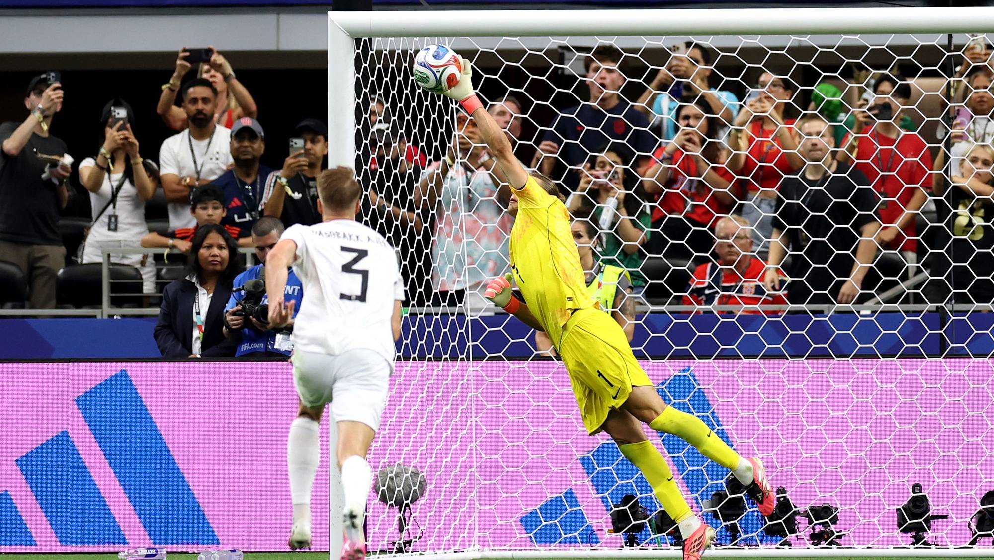 Kroatias keeper redder et skudd fra en motspiller under en fotballkamp. Publikummere ser på. (Bildebeskrivelsen er laget av en KI-tjeneste)
