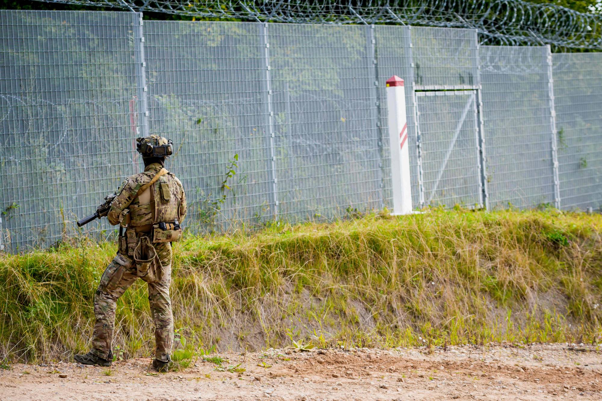 A State Border Guard stands near a fence during a visit of the Latvian President at the Latvian-Belarusian border on August 17, 2026 in Piedruja, Latvia. (Photo by Gints Ivuskans / AFP)