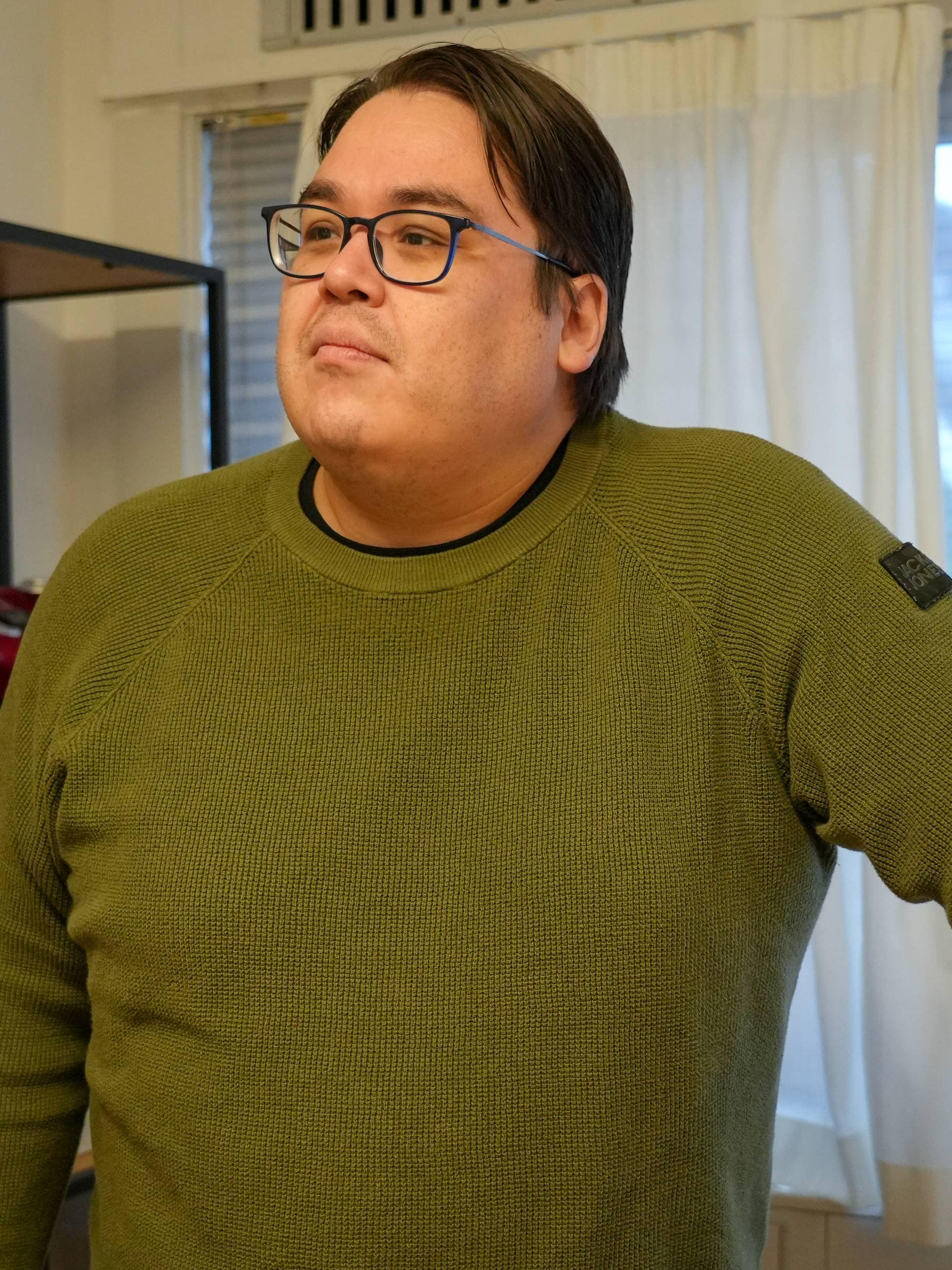 Bilde av Aqqalu C. Jerimiassen som ser til siden. Han har armen utstrekt og lener seg litt mot noe