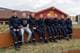 Azora Reinholt / NRK En gruppe på åtte personer sitter i en halvsirkel foran en rød bygning. Seks av personene er kledd i mørkeblå uniformer med reflekser. Bygningen har et stort gult S-symbol. De sitter på en lav vegg av cortenstål. (Bildebeskrivelsen er laget av en KI-tjeneste)