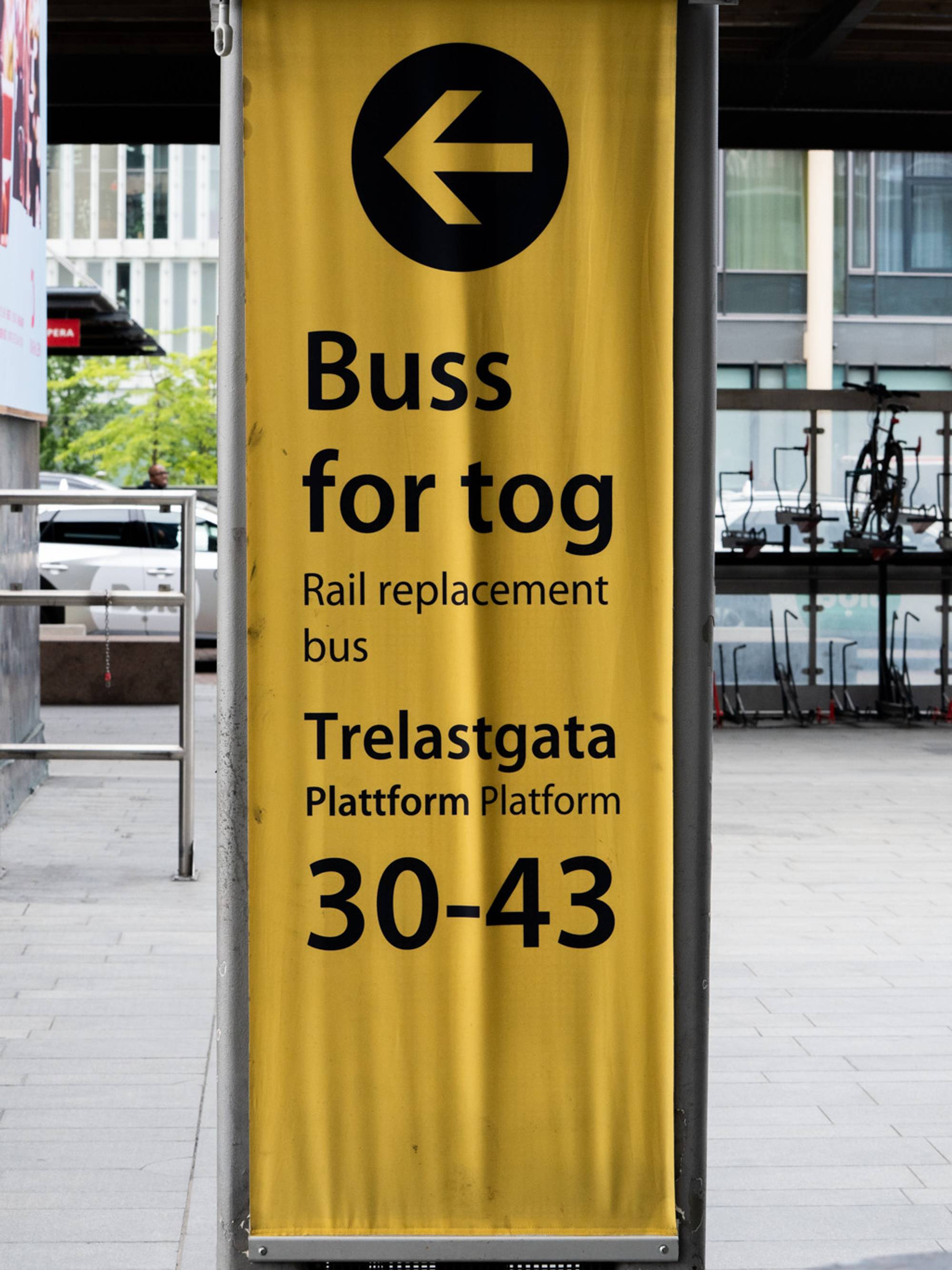 Gult skilt med tekst om buss for tog ved Trelastgata plattform 30-43. 