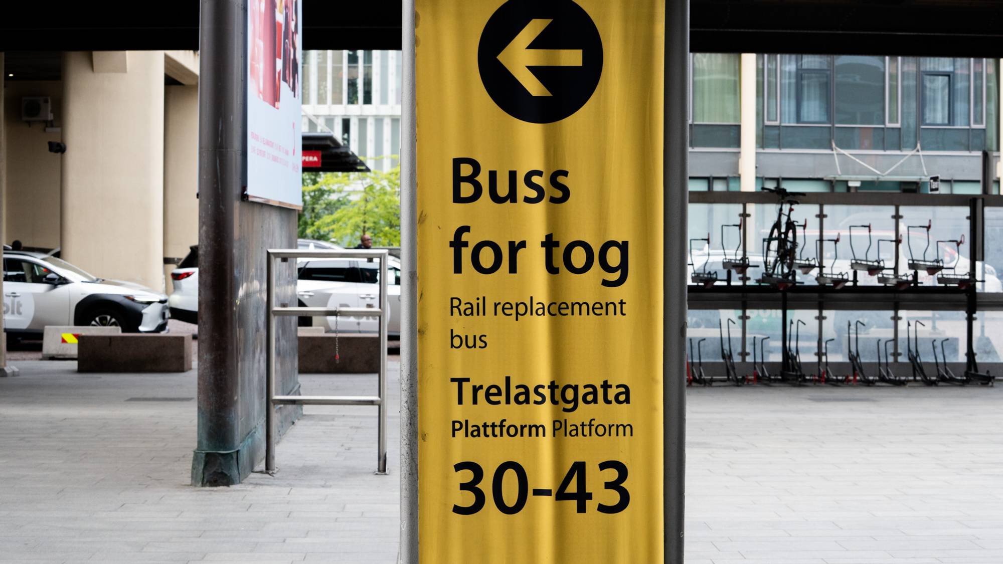 Gult skilt med tekst om buss for tog ved Trelastgata plattform 30-43. 