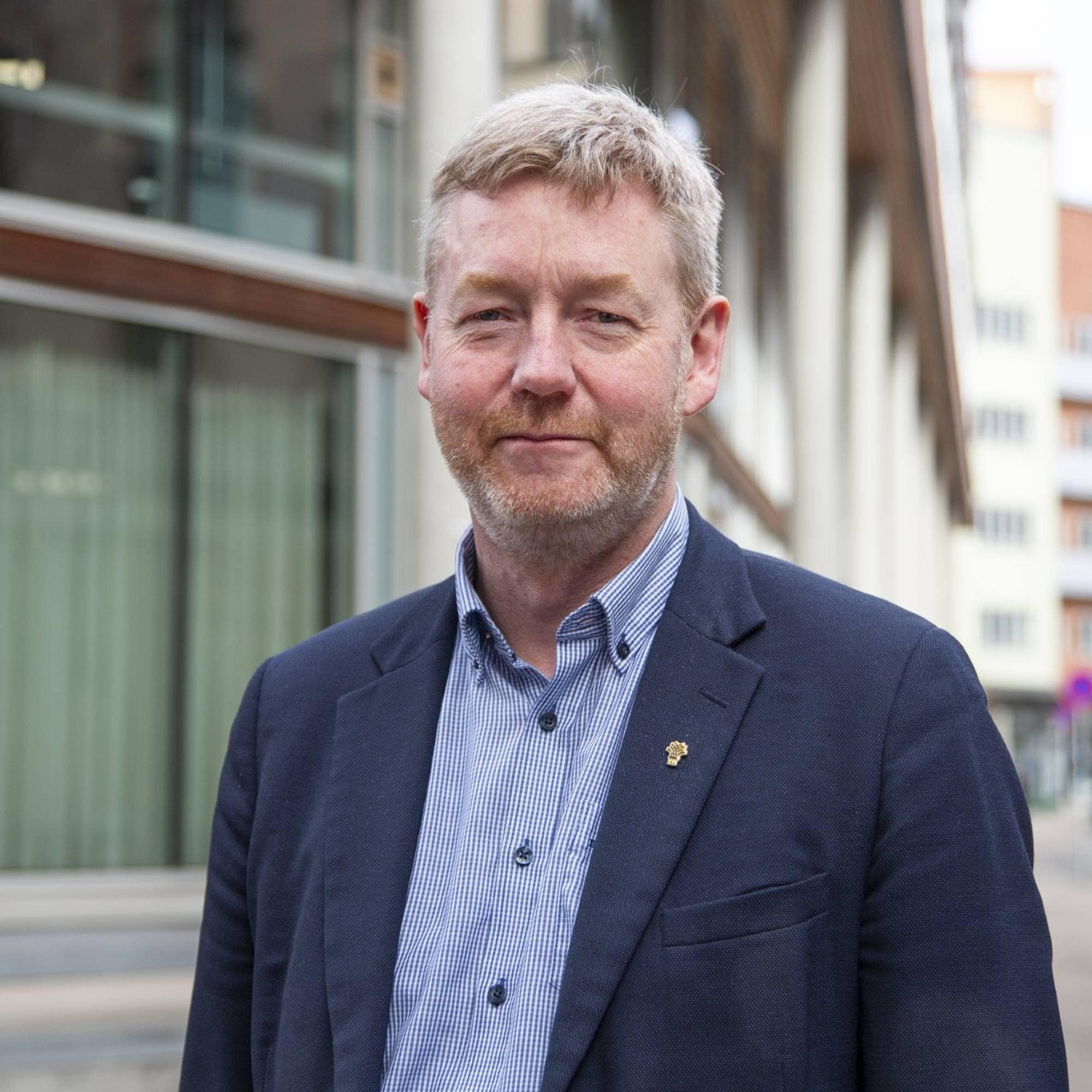 Bjørn Gimming, leder Norsk Bondelag, halvportrett foran bygg med store vinduer.