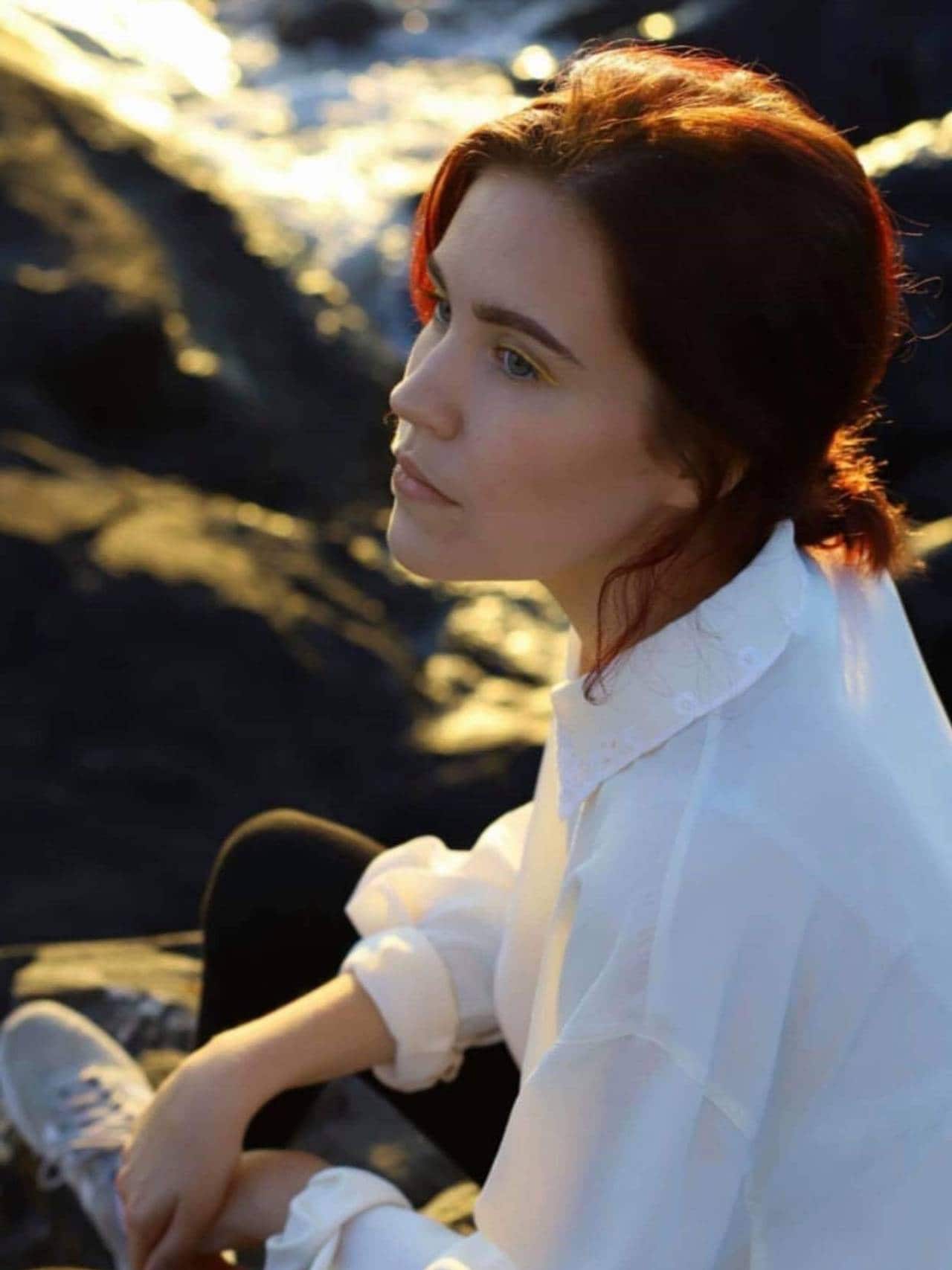 Bilde av en tankefull Cecilie som sitter ute i lav sol