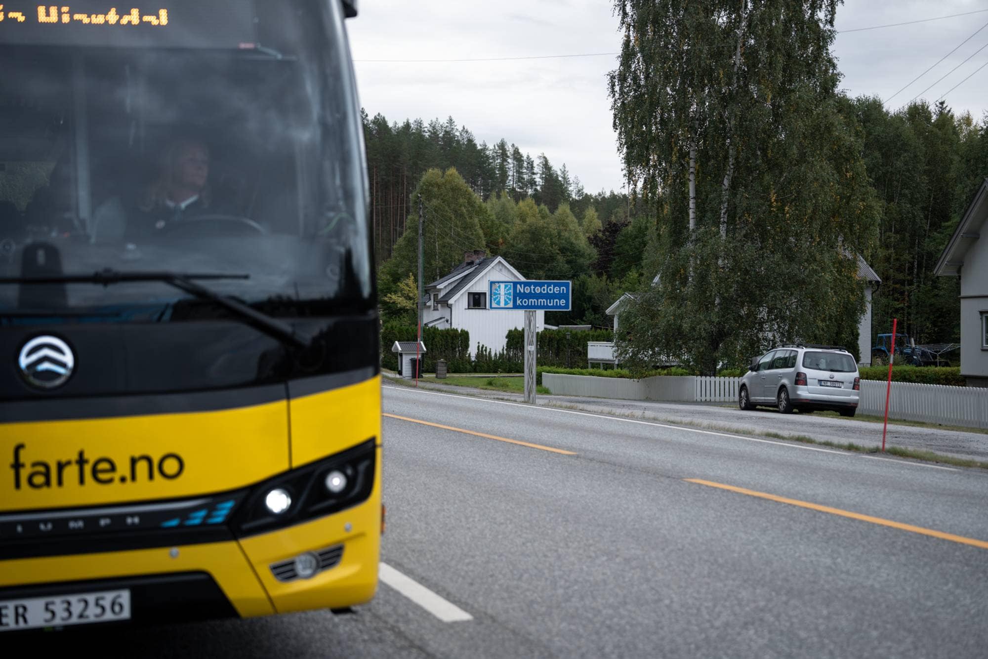 Gul buss kjører forbi et skilt merket Notodden kommune. 