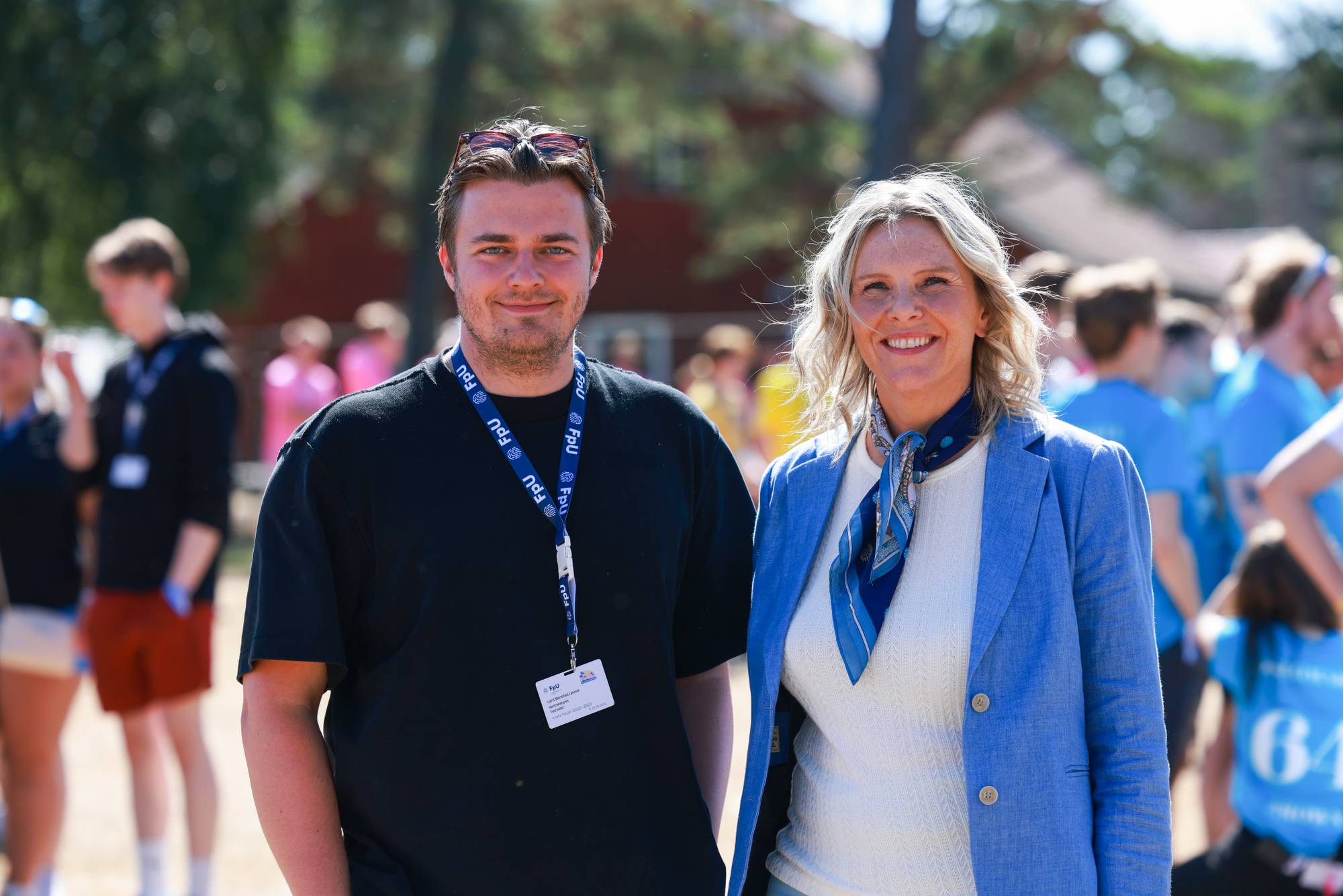 Lars Barstad Løvold og Sylvi Listhaug står side om side utendørs. I bakgrunnen er folk i blå t-skjorter. (Bildebeskrivelsen er laget av en KI-tjeneste)