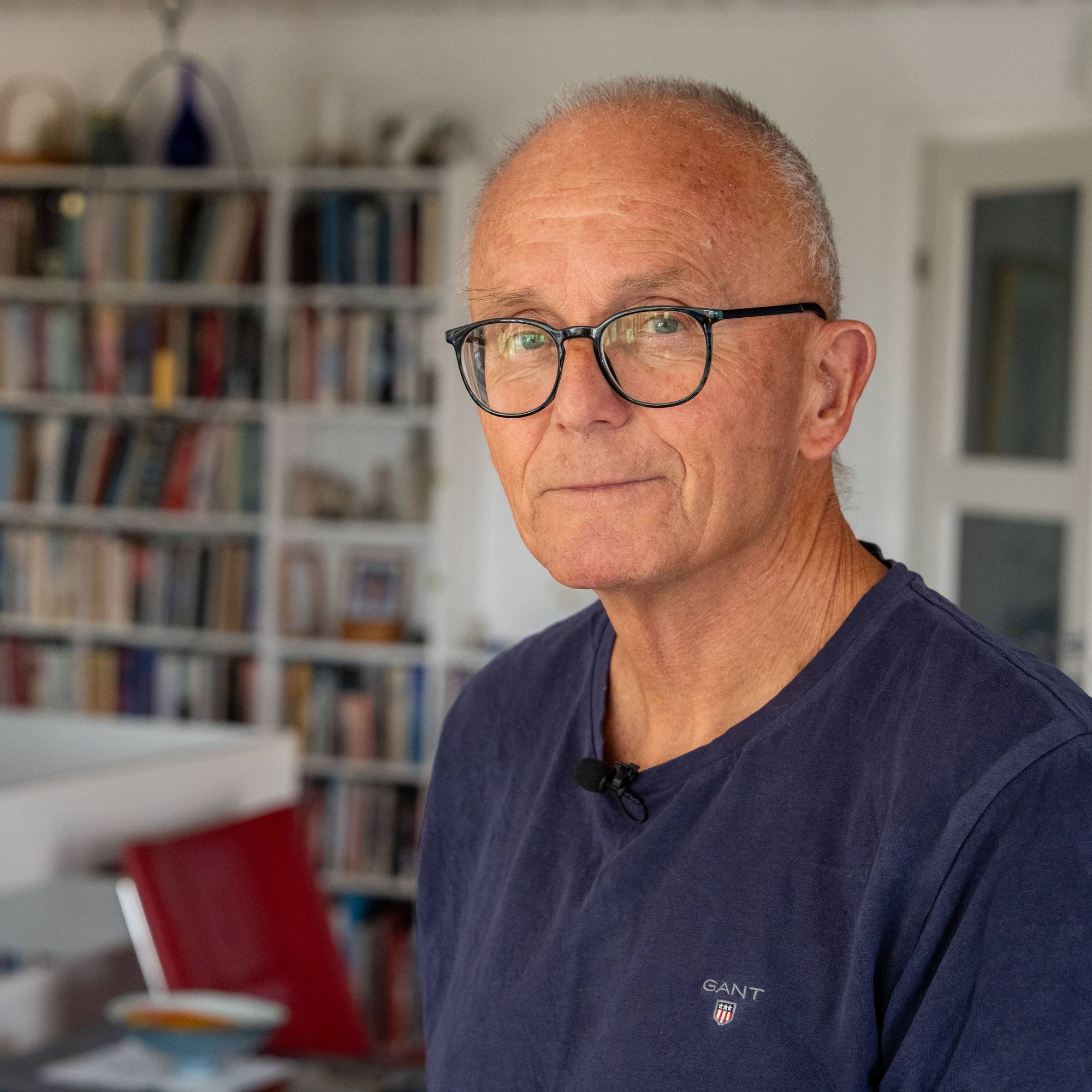 En mann med briller ser i kameraet

