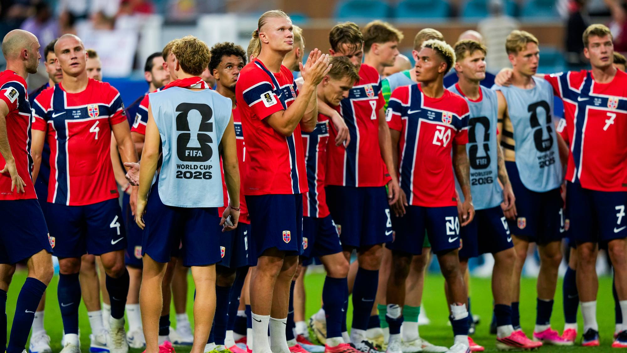 Det norske herrelandslaget i fotball står på banen etter en kamp. Spillerne bærer røde landslagsdrakter. (Bildebeskrivelsen er laget av en KI-tjeneste)