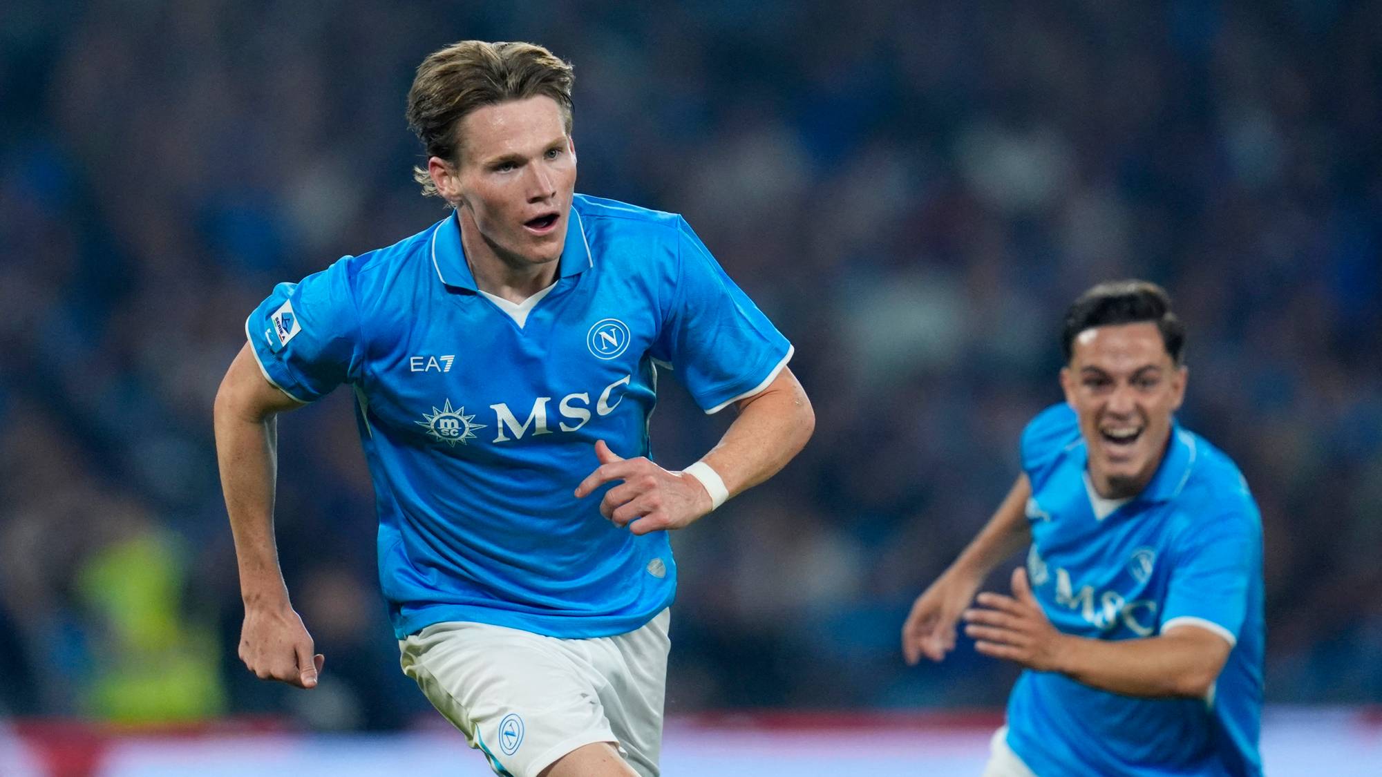 Leo Skiri Østigård løper på banen i Napoli-drakt mens en lagkamerat følger etter. (Bildebeskrivelsen er laget av en KI-tjeneste)