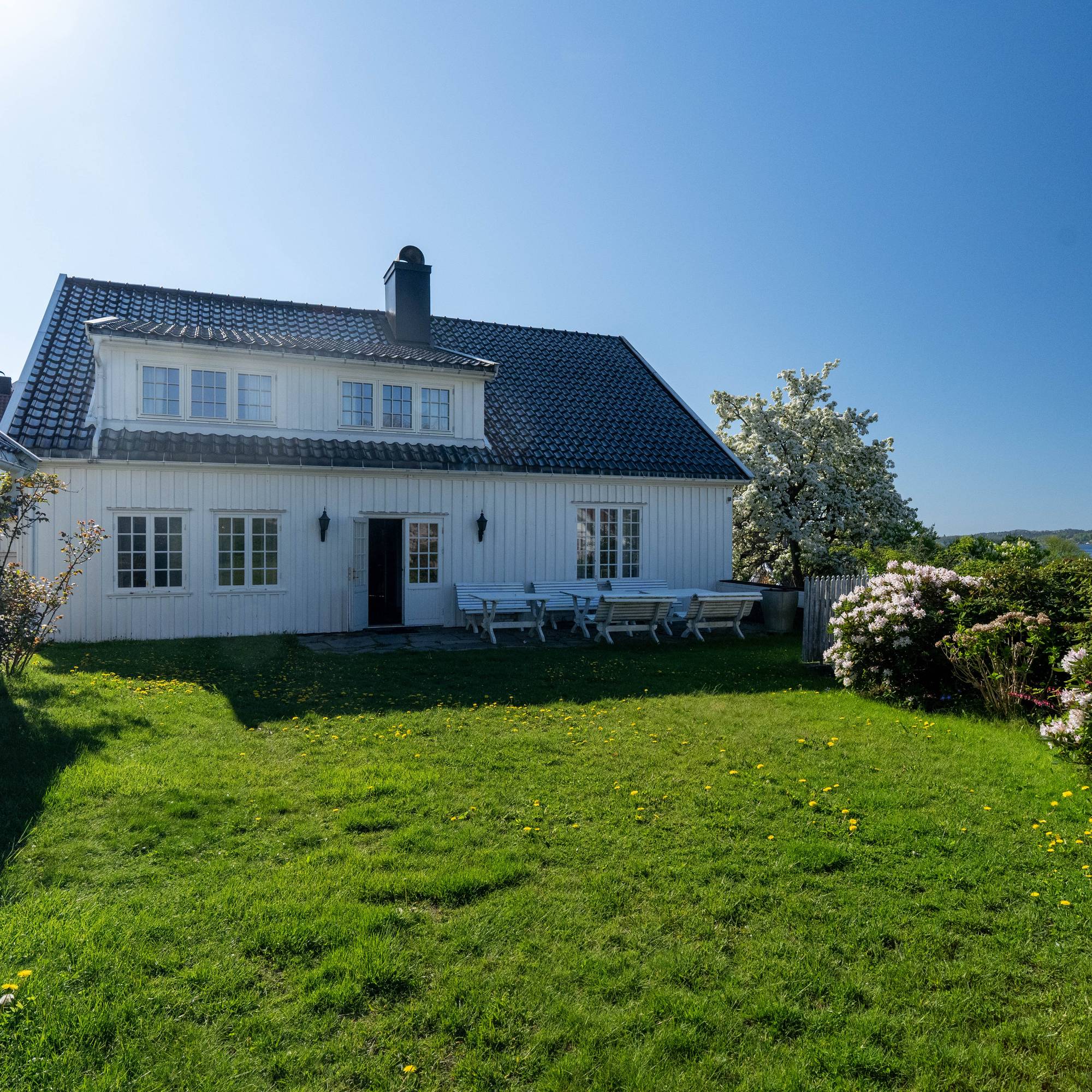et stort hus med plen foran seg (Bildebeskrivelsen er laget av en KI-tjeneste)
