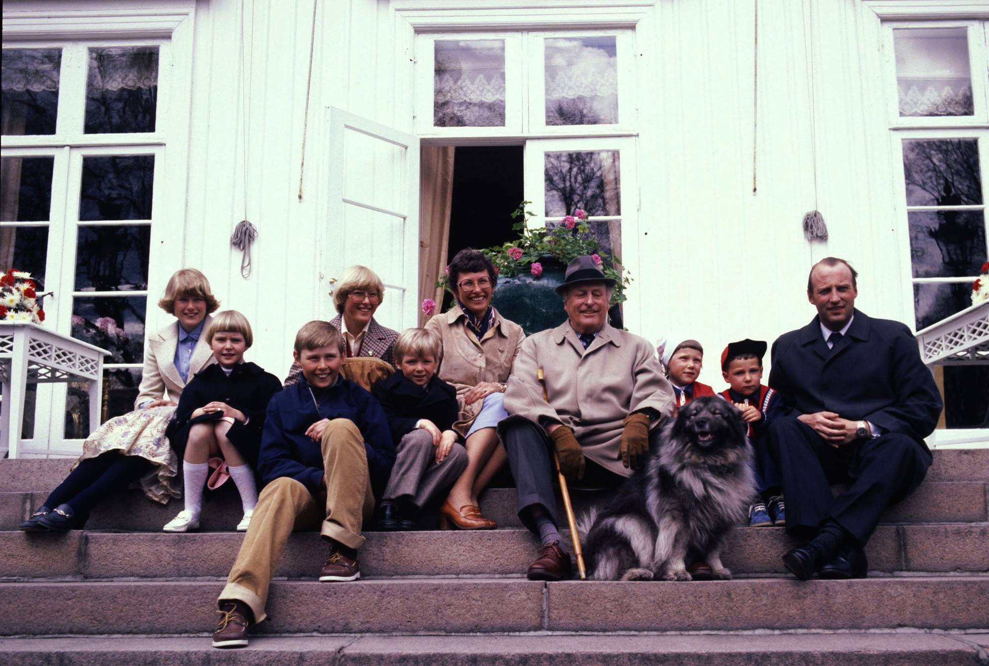 Kong Olav med daværende kronprins Harald og prinsesse Astrid og deres barn, sitter på trappa på Bygdøy kongsgård