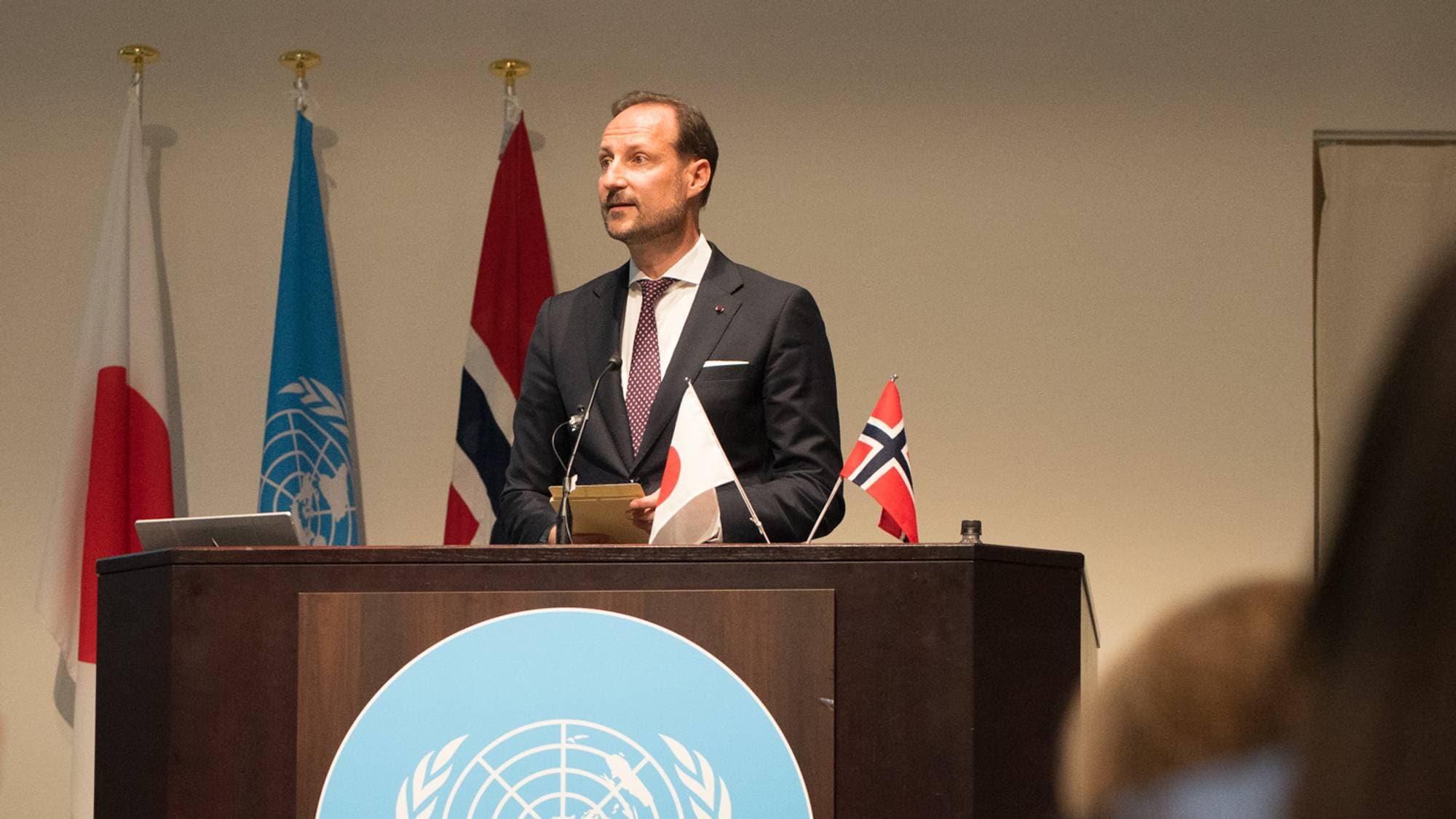 en person som står ved en talerstol (Bildebeskrivelsen er laget av en KI-tjeneste)