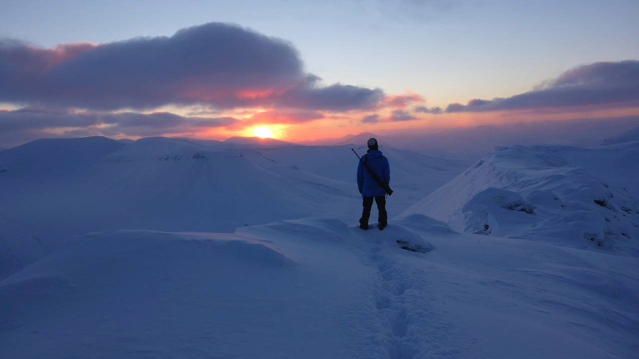 Stian Aadland ser ut over fjellene på Svalbard når sola forsvinner