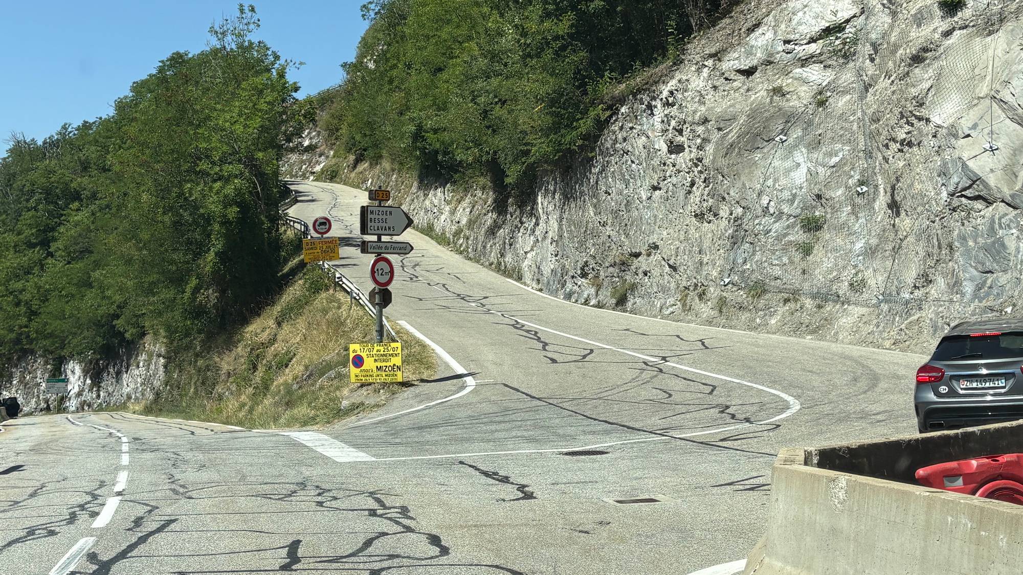 Smal fjellvei med skilting om stengt vei og parkering forbudt i forbindelse med Tour de France. (Bildebeskrivelsen er laget av en KI-tjeneste)