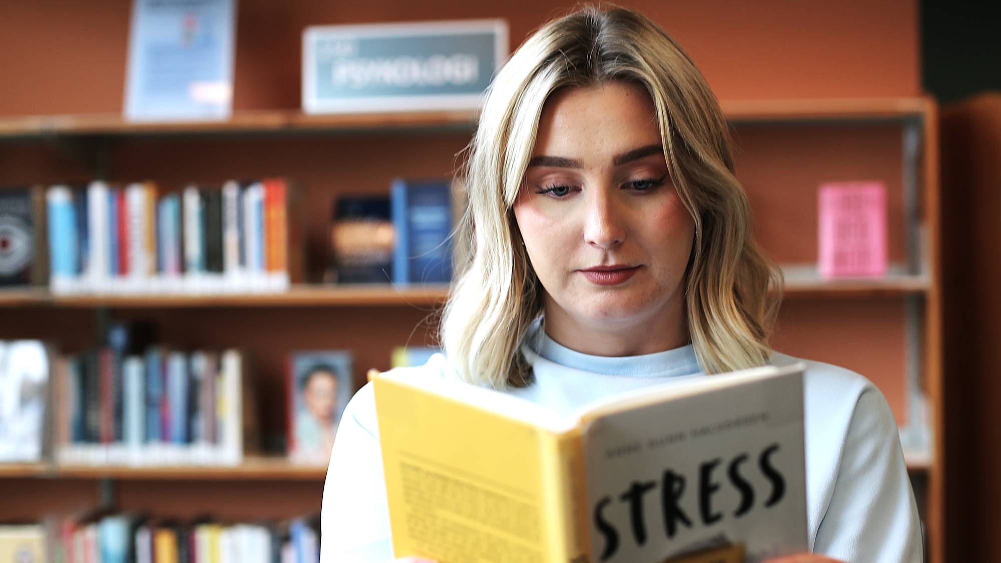 Ung kvinne leser en bok om stress