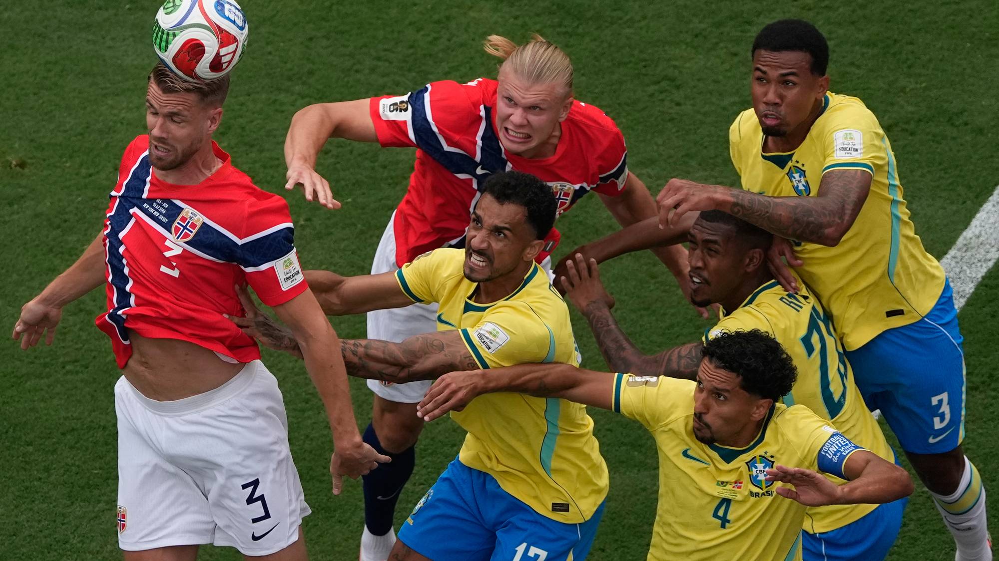 Fotballspillere fra Norge og Brasil kjemper om en hodeduell i en fotballkamp. (Bildebeskrivelsen er laget av en KI-tjeneste)
