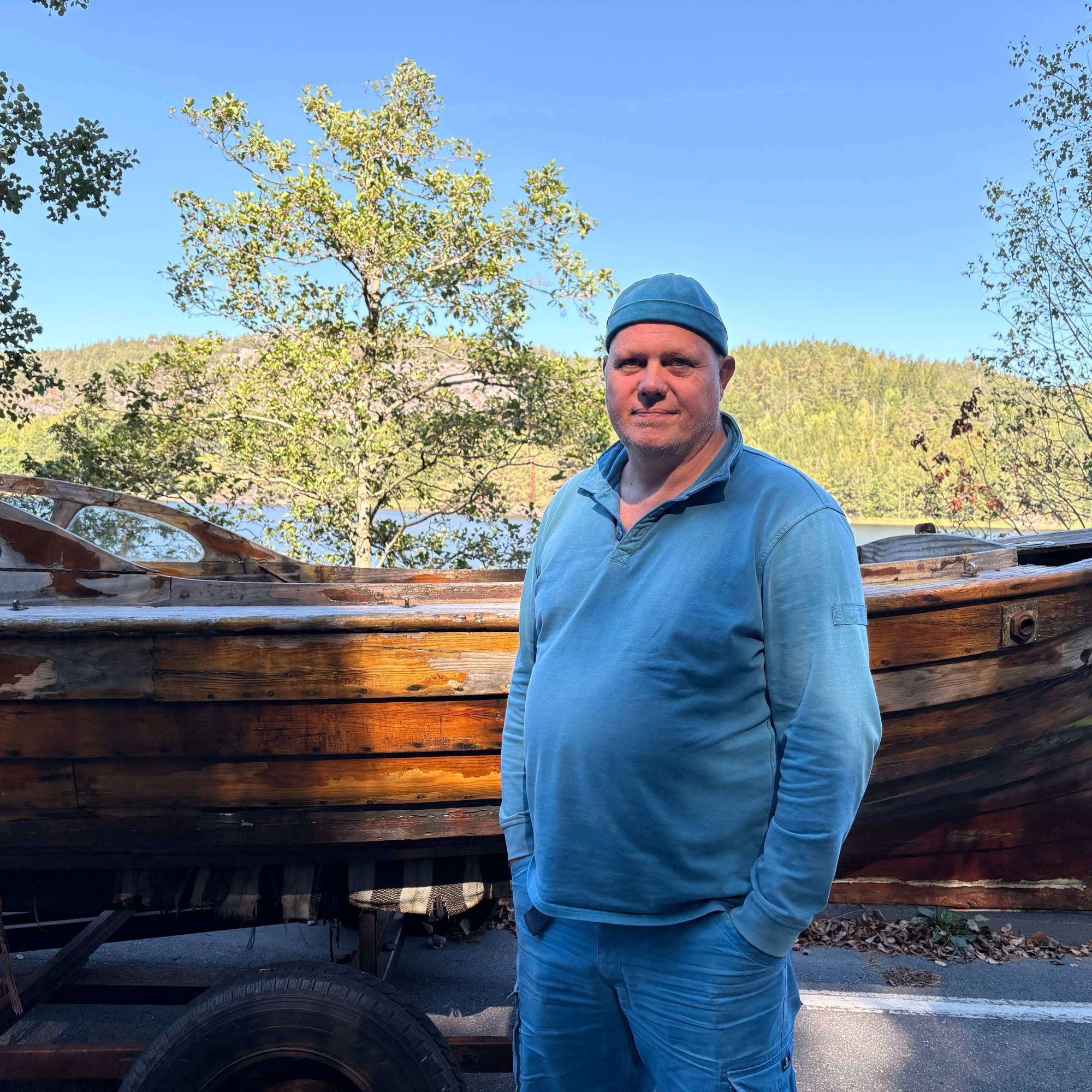 En mann står ved siden av en båt