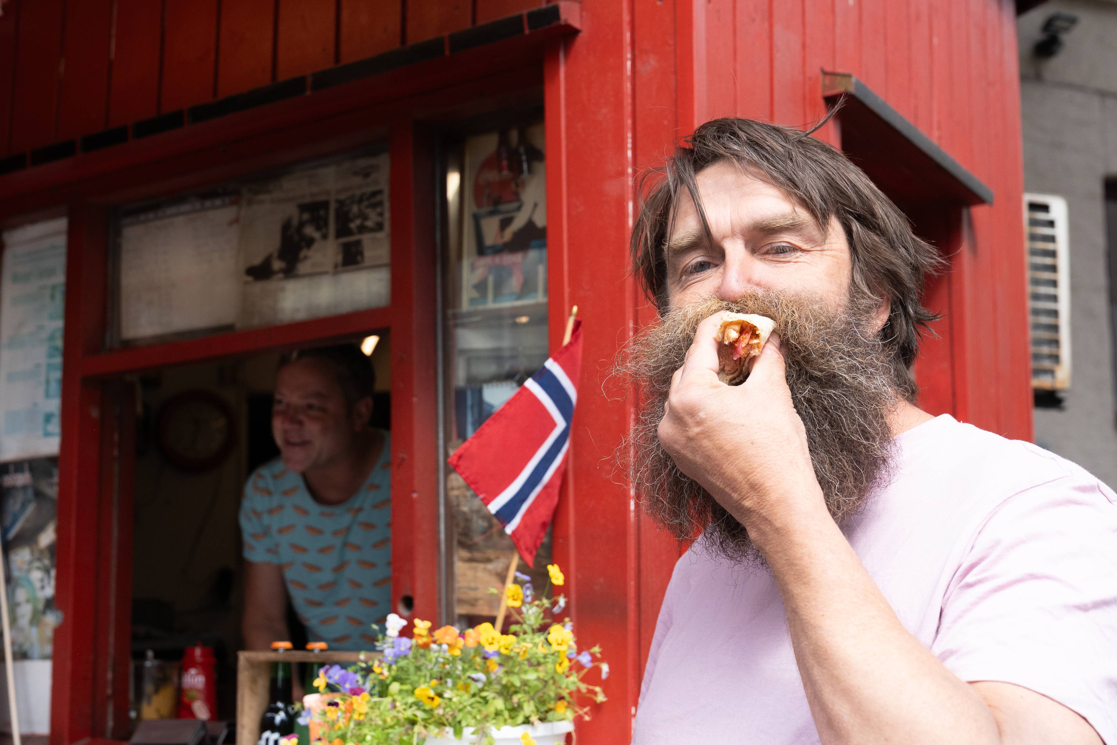 en mann med skjegg som spiser en pølse