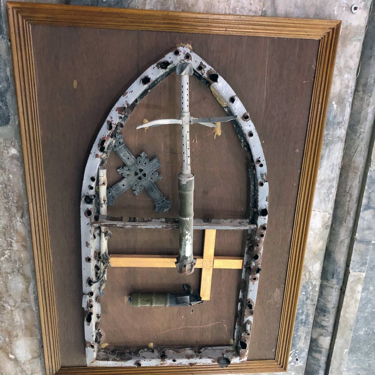 Det gamle vinduet fra den gamle kirken i Qaraqosh er pepret med kulehull og satt i ramme.