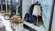 Foto: Nadir Alam / NRK Vinduet til en butikk er knust, med store glassbiter som ligger på bakken. Inne i butikken henger klær på stativ, inkludert gensere og bukser. (KI)