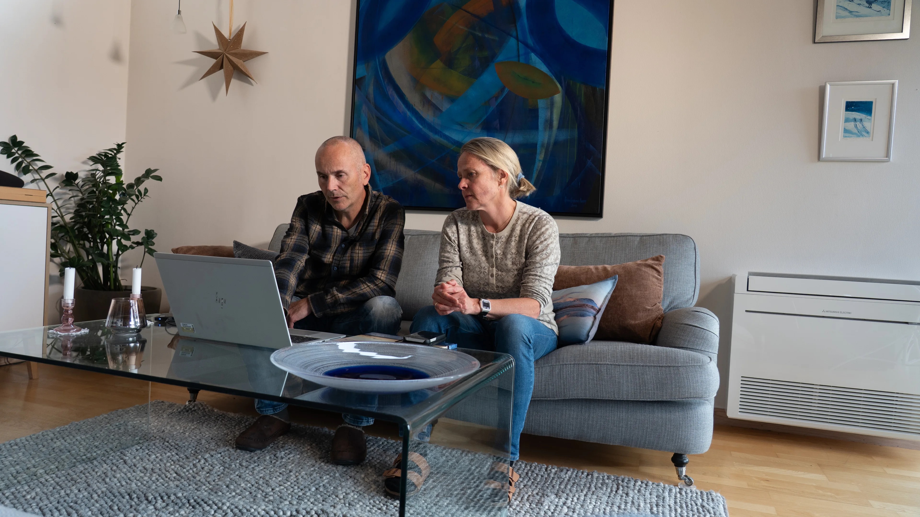 en mann og en kvinne som sitter på en sofa med en bærbar datamaskin