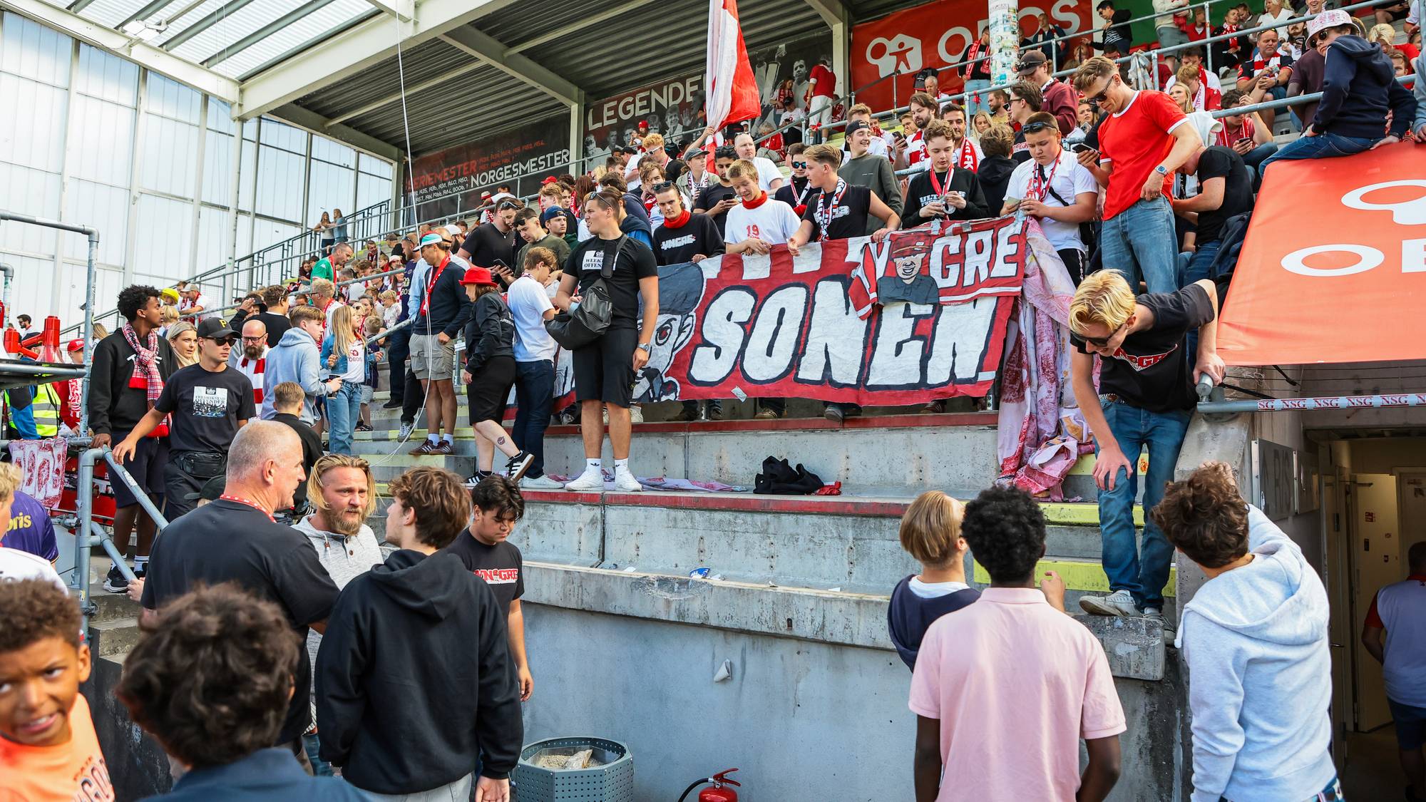 Supportere på tribunen holder et banner med påskriften Sønnen under en fotballkamp. (Bildebeskrivelsen er laget av en KI-tjeneste)