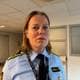 Bettina Olie Bjerkholdt / NRK En kvinnelig politibetjent står i en offentlig bygning, iført uniform og ID-kort. Omgivelsene inkluderer en sofa og informasjonstavler på veggene. Det er lav belysning og et industrielt preg. Betjenten ser mot kameraet og har langt hår.