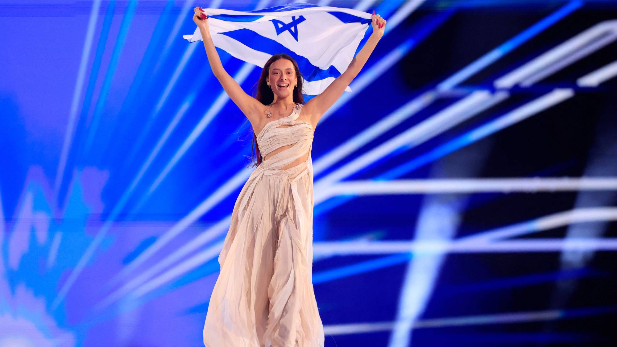 Eden Golan i en kjole som holder et flagg
