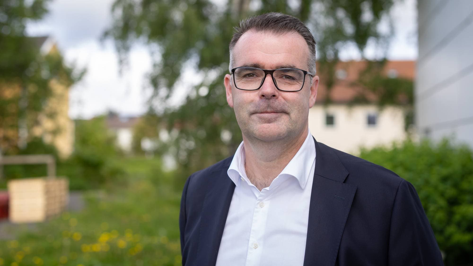 Kent Ranum har på seg briller, hvit skjorte og blå dress. Han ser inn i kameraet.