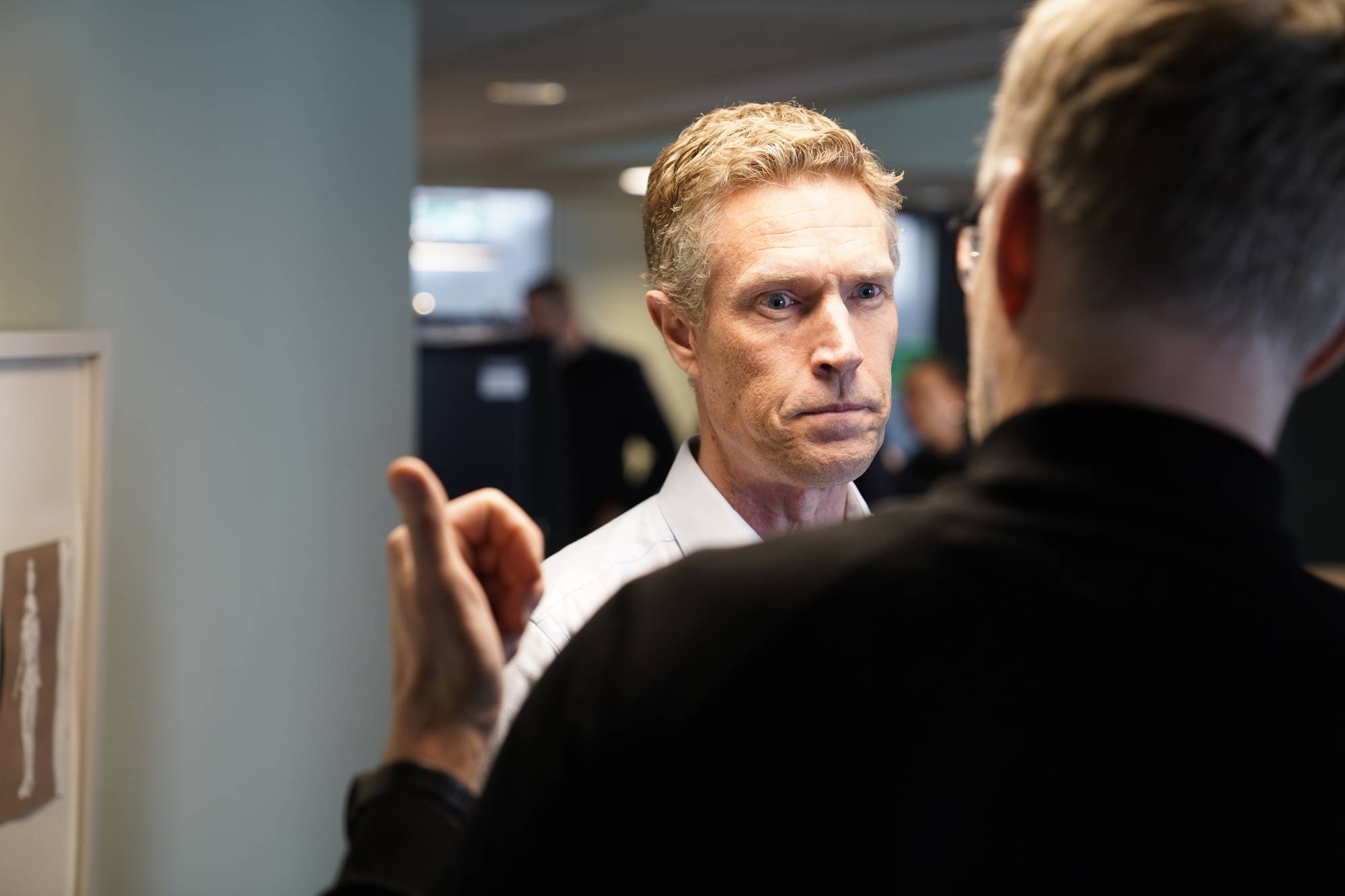 Mann med lyst hår og hvit skjorte ser i kamera