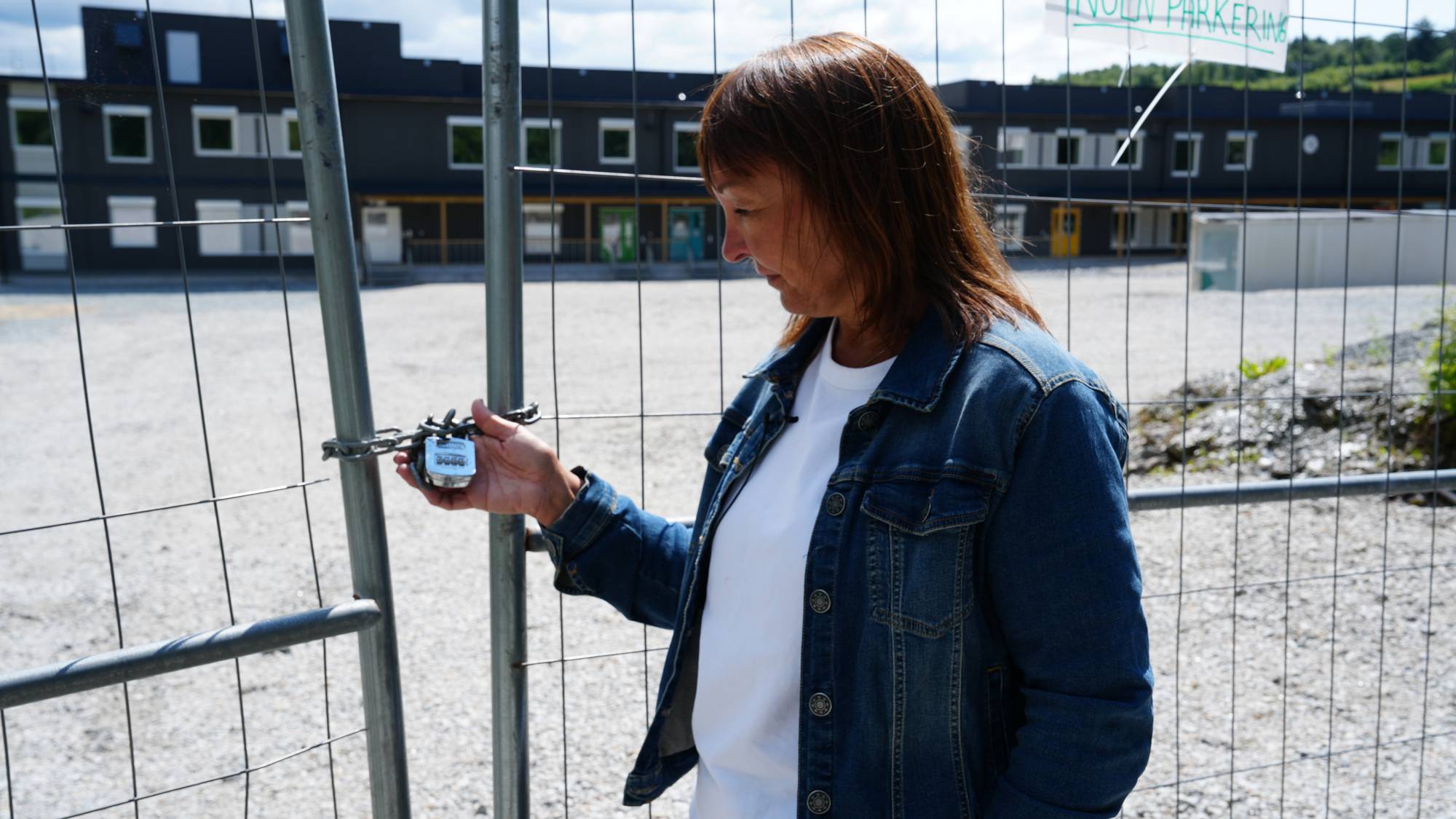 Rektor ved Vaulen skole holder en hengelås utenfor modulskolen i Sørmarka.