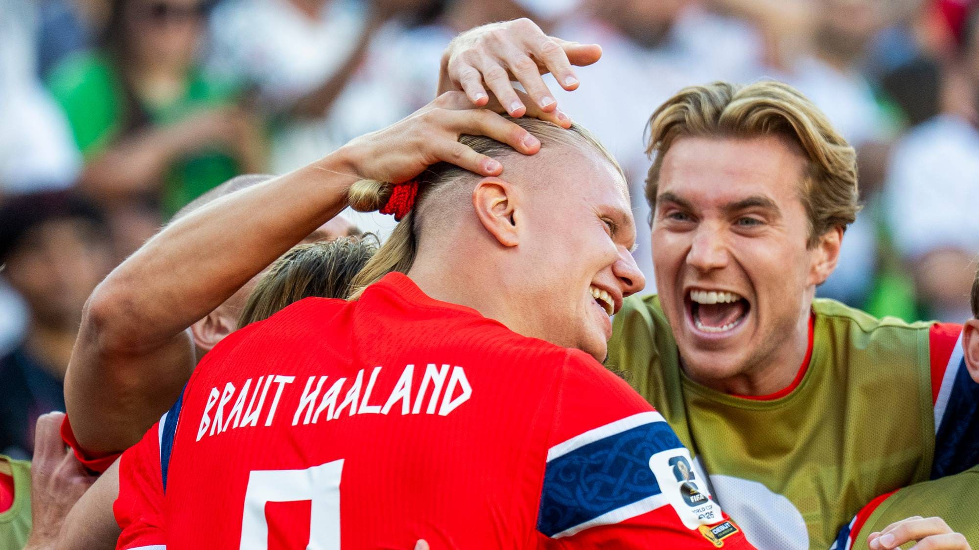 Flere fotballspillere feirer sammen etter en kamp. Spillerne er kledd i røde drakter med norske flaggdetaljer. En av spillerne har navnet "BRAUT HAALAND" på ryggen. (Bildebeskrivelsen er laget av en KI-tjeneste)