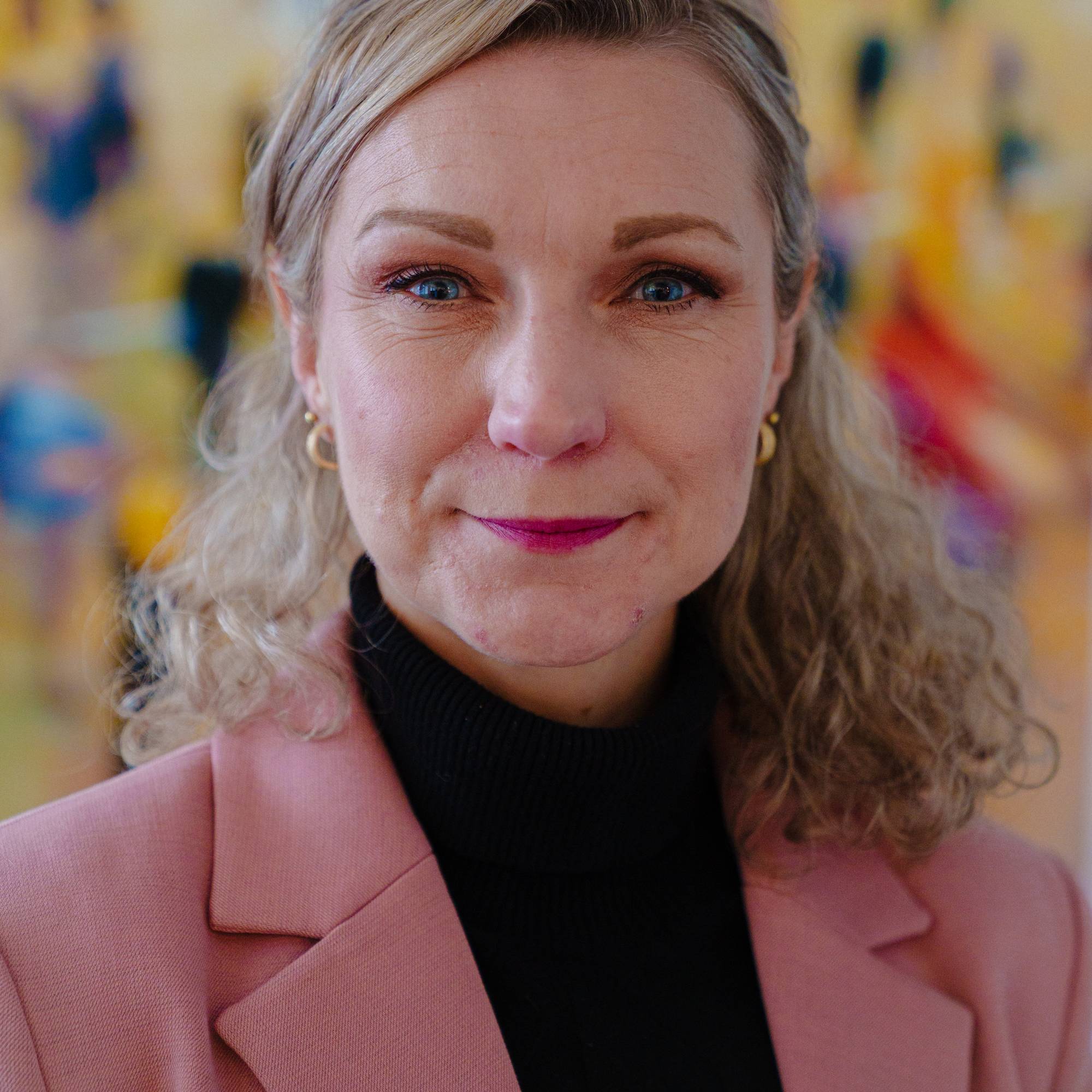 Portrett av Karianne Tung som står foran en fargefull bakgrunn
