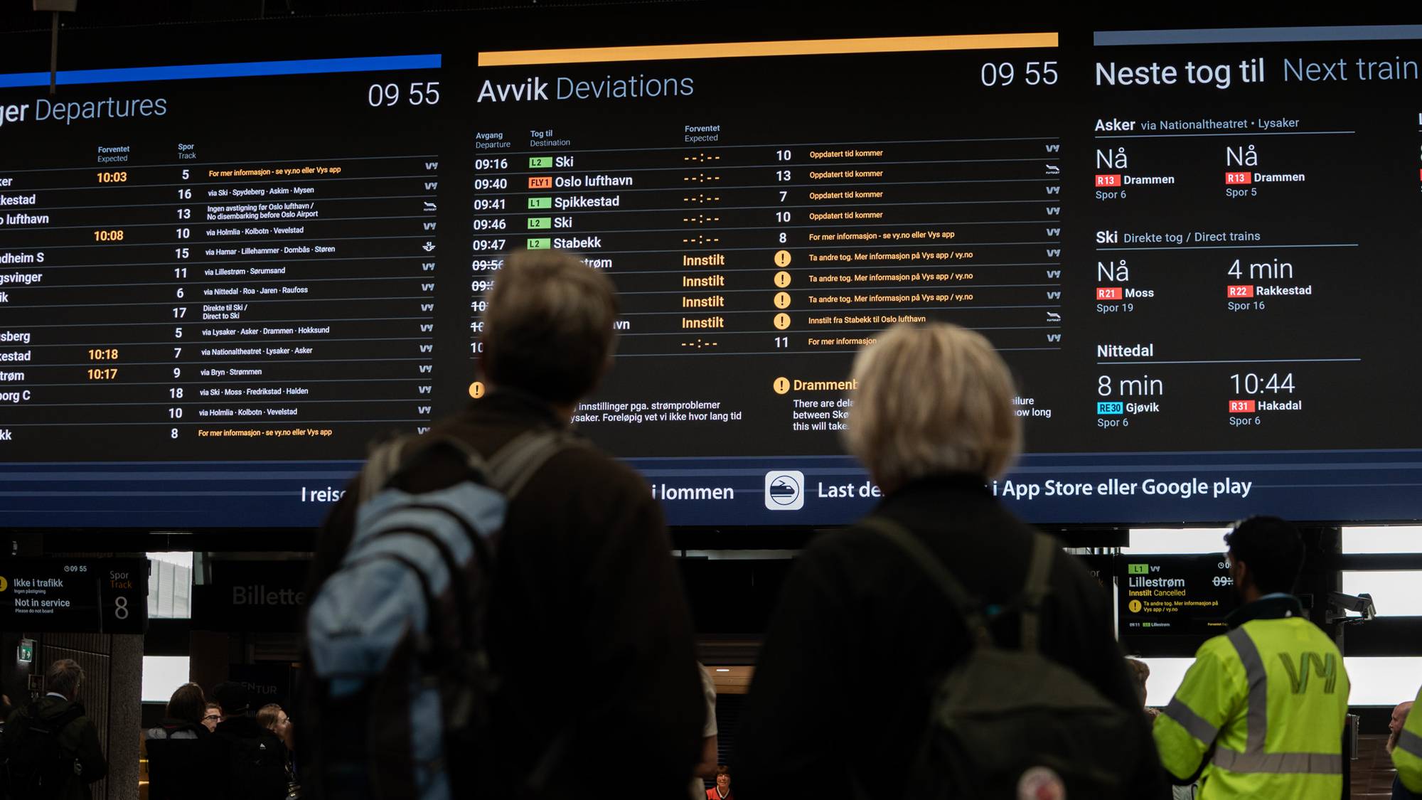 Reisende ser på en informasjonstavle som viser toginnstillinger på en stasjon. 