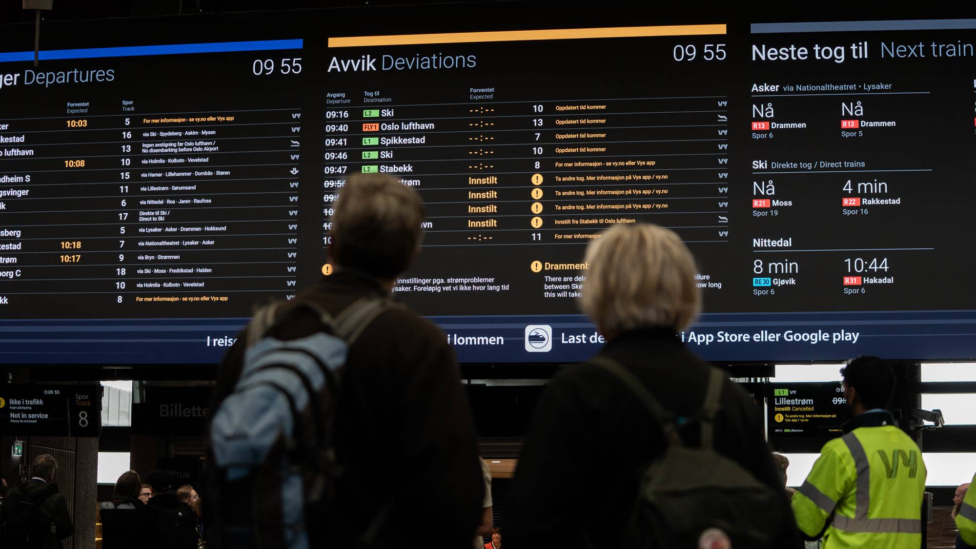 Reisende ser på en informasjonstavle som viser toginnstillinger på en stasjon. 