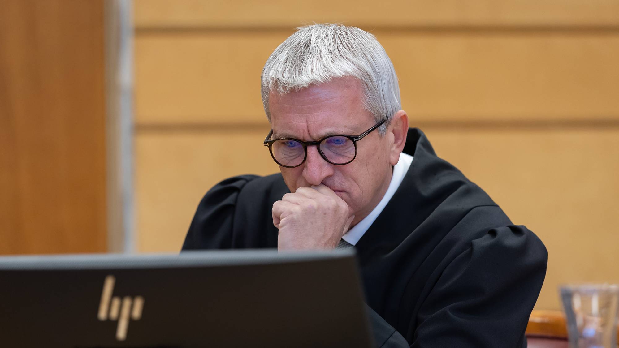 Forsvarer Kolbjørn Margido Lium sitter i en rettssal. Han er iført svart kappe. Han kikker på en PC og holder den ene hånden opp til ansiktet. Han virker konsentrert