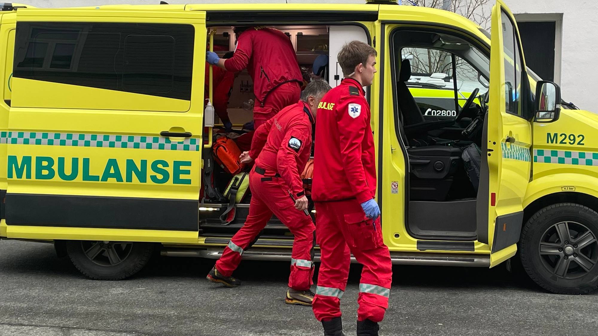 En gruppe mennesker i røde jumpsuits som står ved siden av en gul varebil