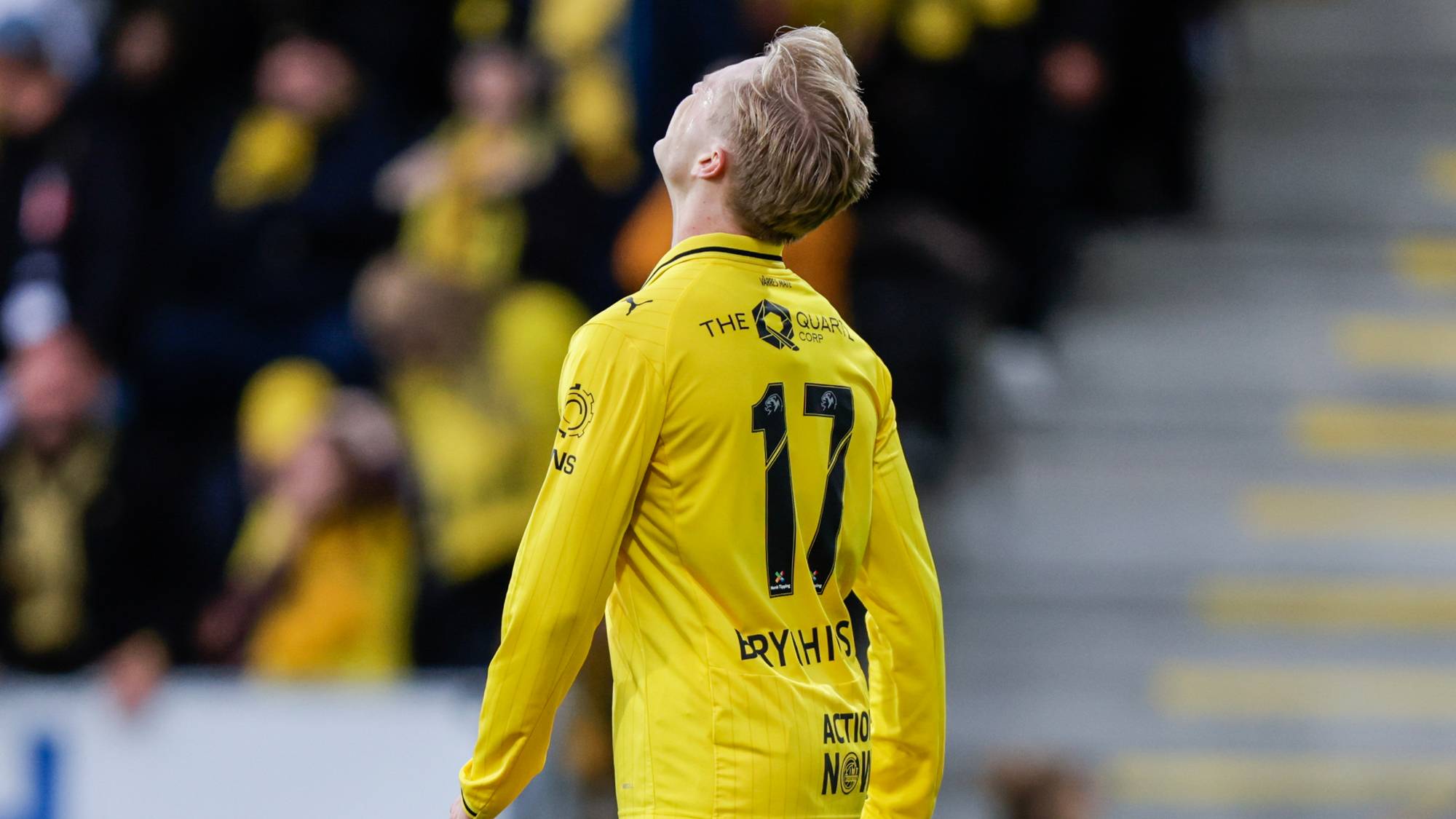Fotballspiller i gul drakt med nummer 17 ser oppover på en fotballstadion. (Bildebeskrivelsen er laget av en KI-tjeneste)