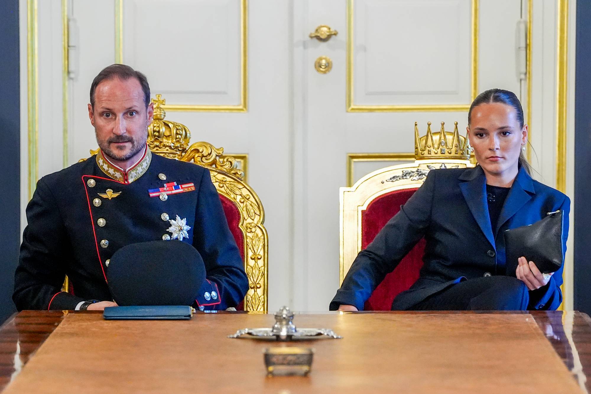 Kronprins Haakon og prinsesse Ingrid Alexandra sitter ved et bord i en høytidelig ramme. (Bildebeskrivelsen er laget av en KI-tjeneste)
