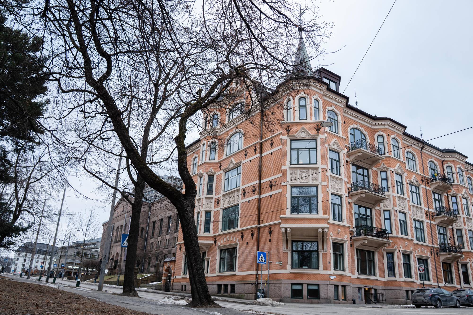 En bygning i oransje murstein med hvite detaljer og svarte balkonger. Bygningen har flere spir og mye utsmykning. Det er høyre trær i forgrunnen og litt snø på gata. 