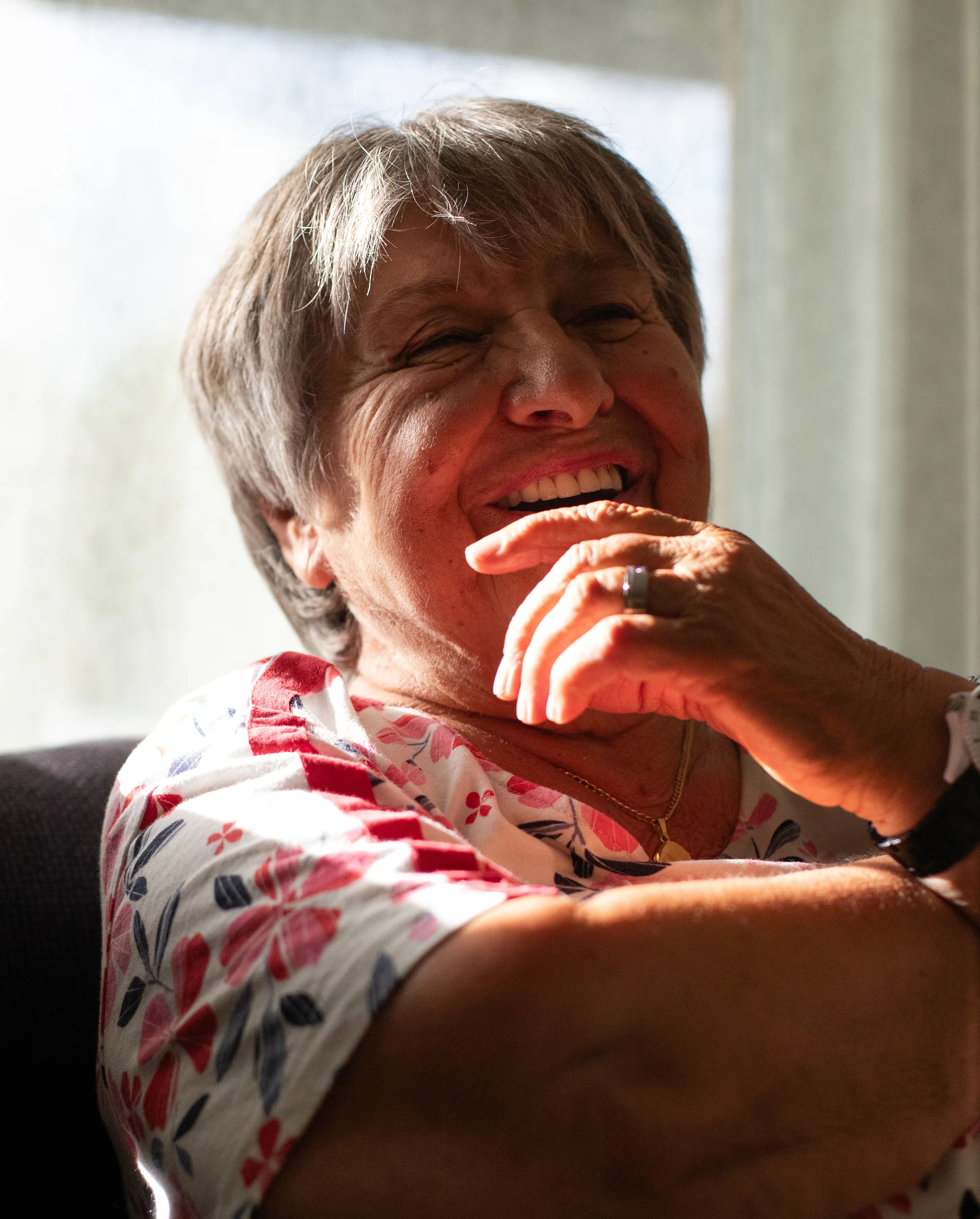 en eldre kvinne som sitter i en sofa, lys treffer ansiktet hennes