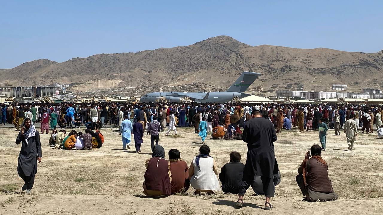 Menneskemengder inne ved rullebanen på flyplassen i Kabul foran et militært transportfly mandag 16. august 2021
