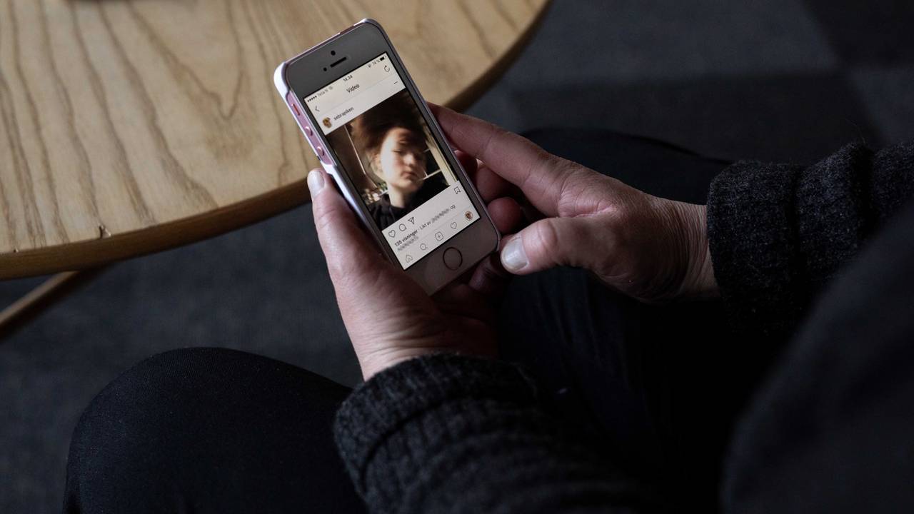 Nærbilde av en hånd som holder en mobiltelefon og ser på Andrines lukkede kontro på Instagram.