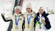 Stephanie Lecocq / Reuters / NTB Tre utøvere står på seierspallen under en medaljeseremoni, iført vinterjakker og luer. To av dem holder opp armene i triumf, mens den tredje smiler og holder kosedyr. Alle tre har medaljer rundt halsen, og omgivelsene er snødekte med en hoppbakke i bakgrunnen. Det er en stemning av feiring og glede. (Bildebeskrivelsen er laget av en KI-tjeneste)
