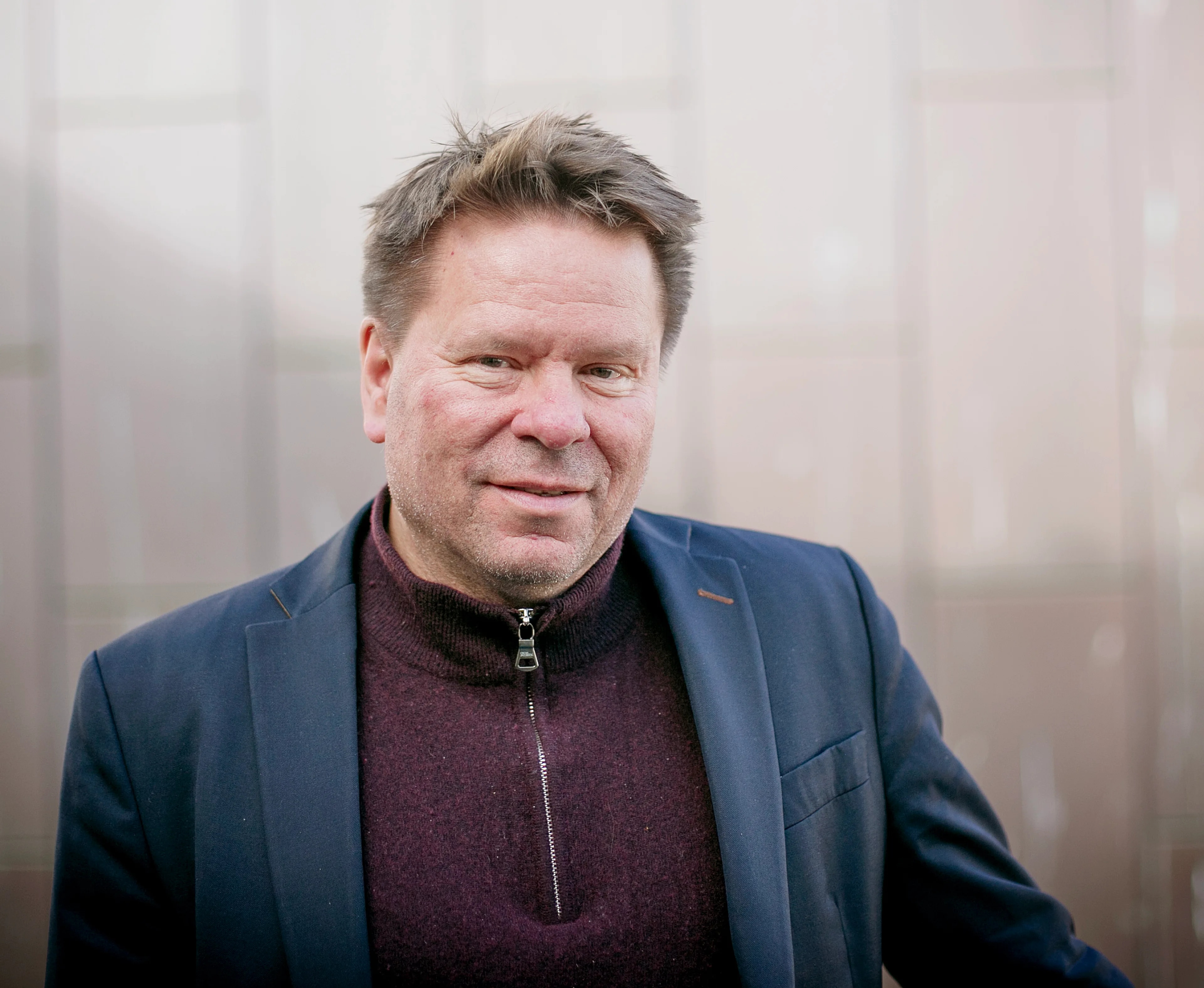 Terje Hernes Pettersen, Sjømannsforbundet, ser rett i kamera. Han har solen delvis i ansiktet og har på seg en plommerød genser med glidlås foran og en mørkeblå dressjakke. Kortklipt brunt hår. Bak ham synes en mursteinsvegg.