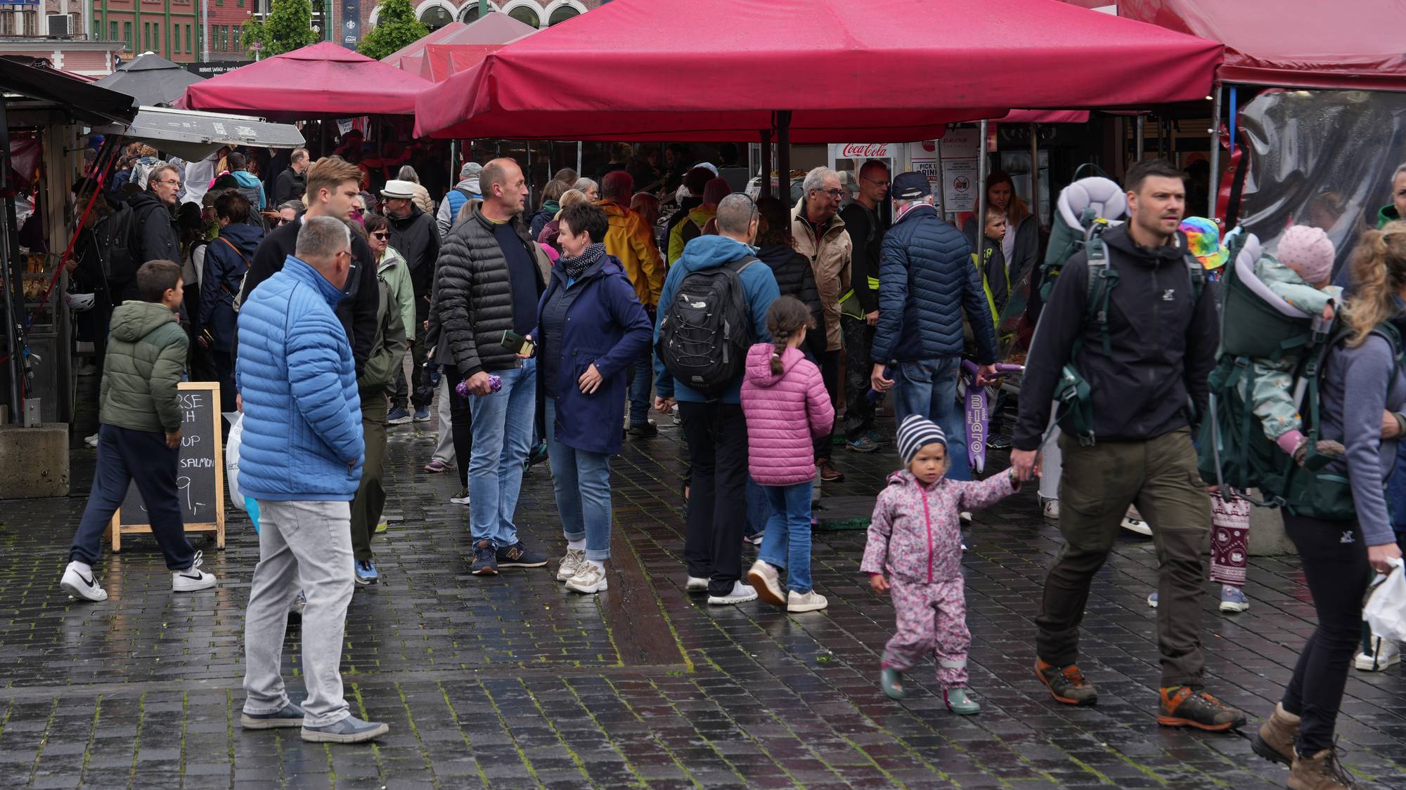 mange menneske framfor raude telt. fleire av dei har boblejakkar, skjerf o gluer