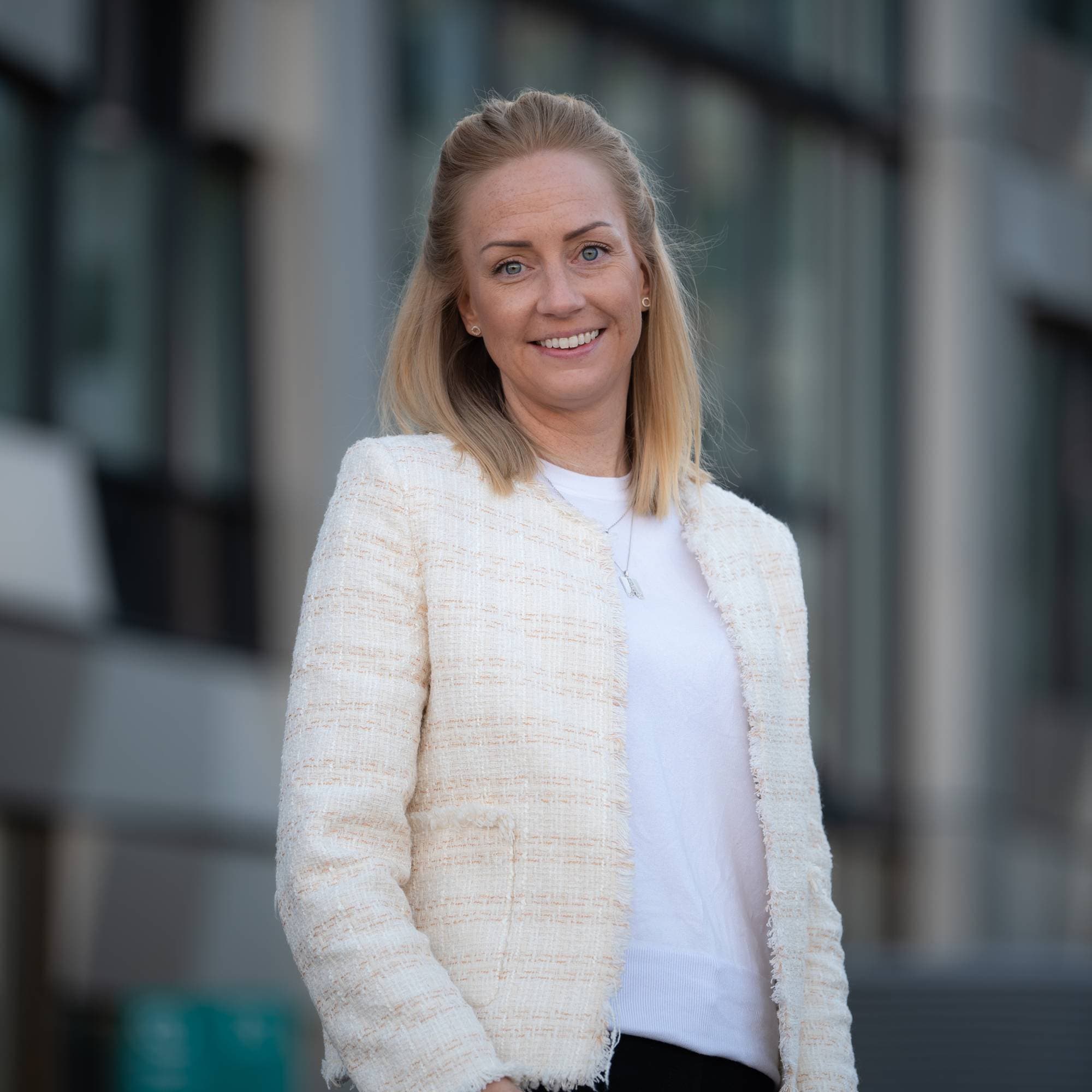Kvinne ser i kamera foran en bygning