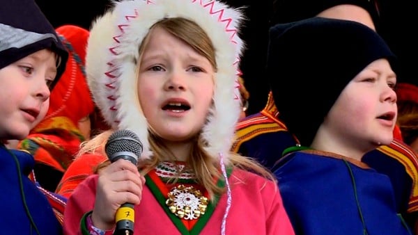 Mina gruer seg til å opptre. Hele skolen er med på den store feiringen av Samenes nasjonaldag i Trondheim. De skal synge og danse på en stor scene. På sørsamisk.